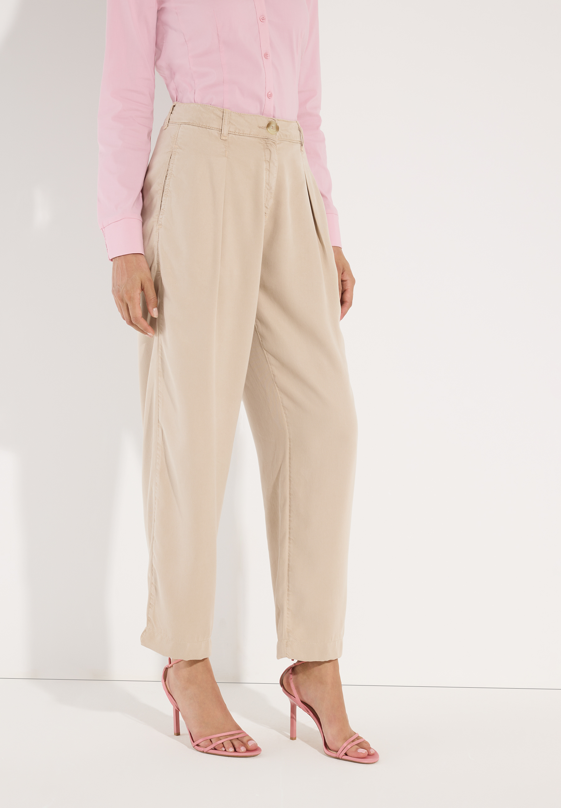 MORE & MORE Jeans: eine beigefarbene Hose aus Webware mit Falten, kombiniert mit einer rosafarbenen Bluse und rosa Sandalen. MORE & MORE Jeans: eine beigefarbene Hose aus Webware mit Falten, kombiniert mit einer rosafarbenen Bluse und rosa Sandalen.