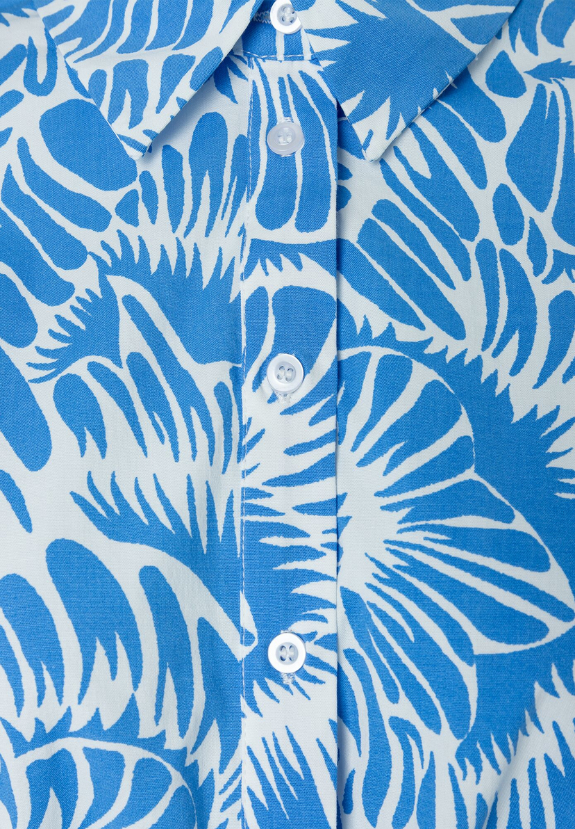 Nahaufnahme einer blau-weiß gemusterten MORE & MORE Bluse mit Knöpfen. Nahaufnahme einer blau-weiß gemusterten MORE & MORE Bluse mit Knöpfen.