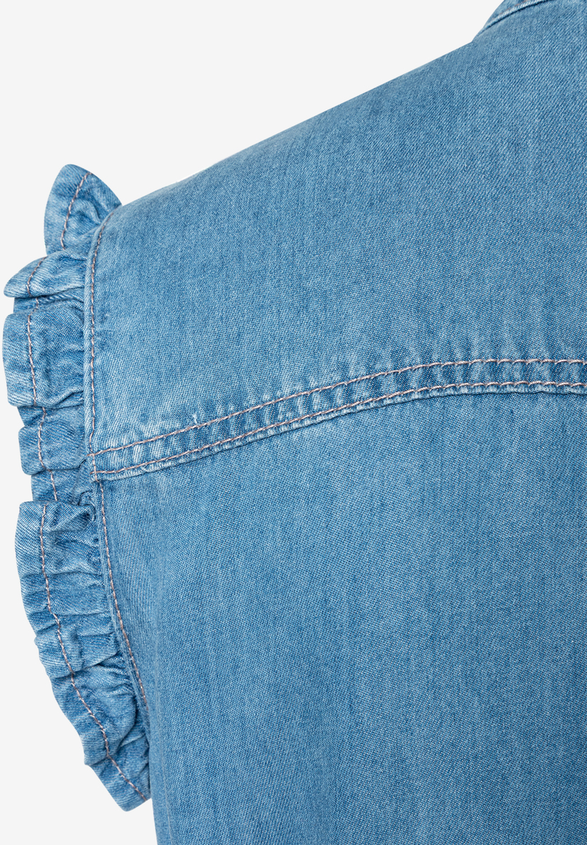 Detailaufnahme eines blauen MORE & MORE Oberteils aus Denim mit Rüschen an der Ärmelpartie. Detailaufnahme eines blauen MORE & MORE Oberteils aus Denim mit Rüschen an der Ärmelpartie.