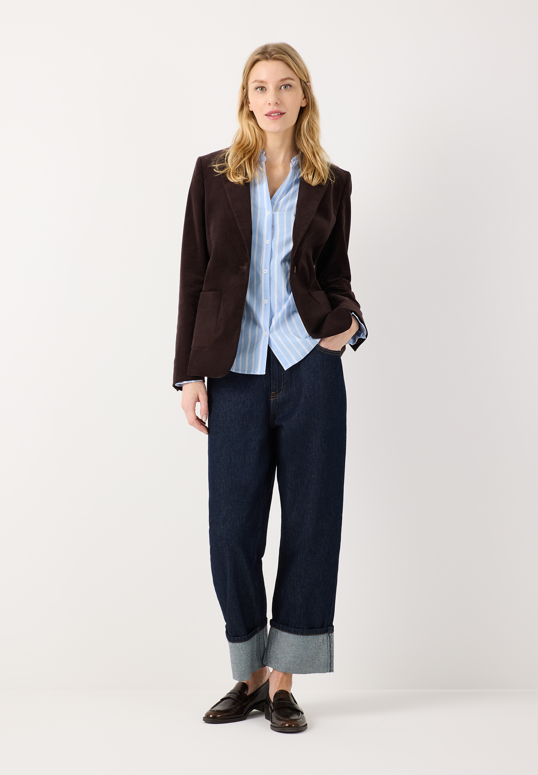 MORE & MORE Blazer: Eine blonde Frau trägt einen dunkelbraunen Blazer über einem hellblauen gestreiften Hemd und dunkelblauen Jeans. MORE & MORE Blazer: Eine blonde Frau trägt einen dunkelbraunen Blazer über einem hellblauen gestreiften Hemd und dunkelblauen Jeans.
