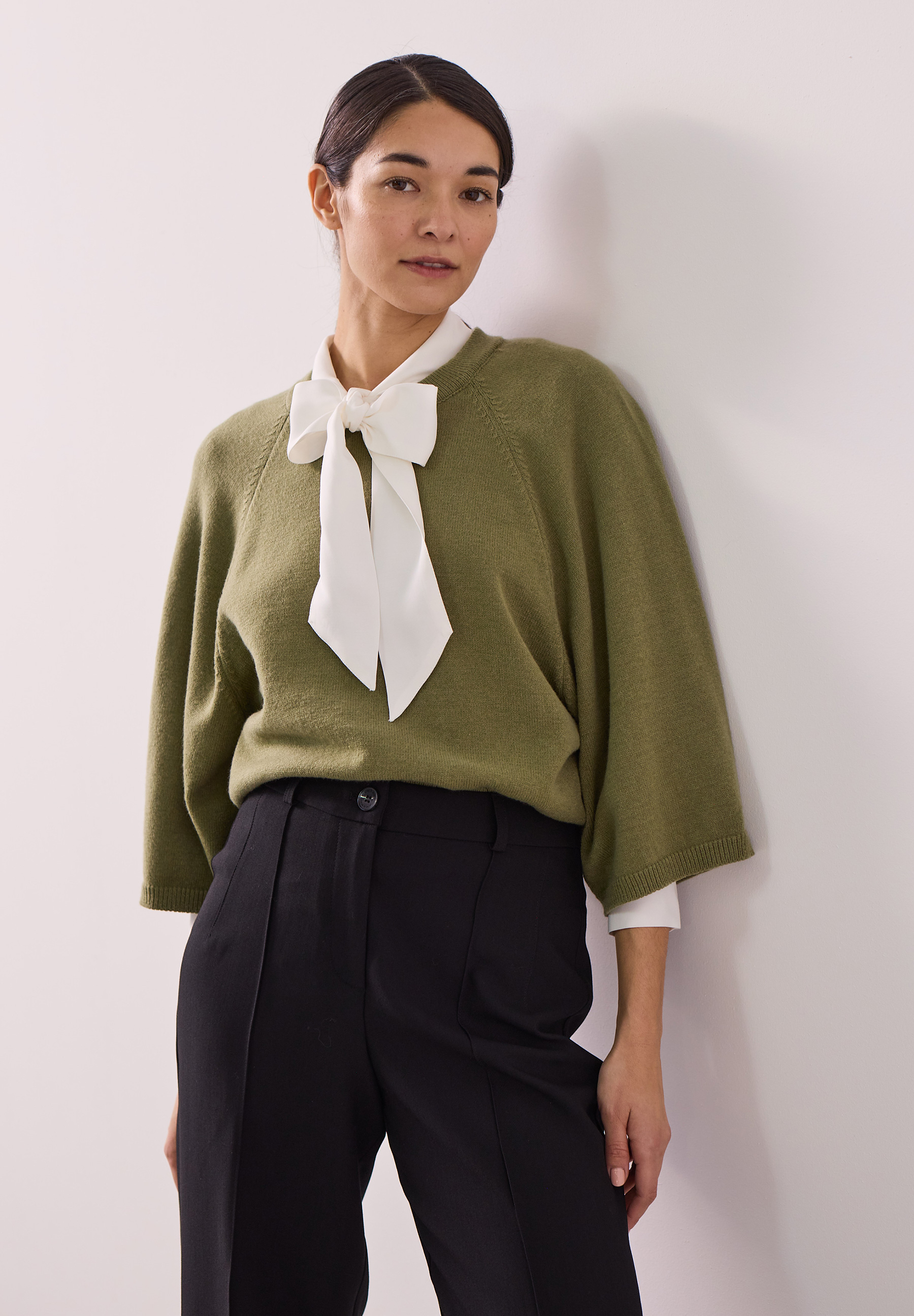 MORE & MORE Pullover: Eine Frau trägt einen khakifarbenen Pullover mit 3/4-Ärmeln, weißer Bluse und schwarzer Hose.