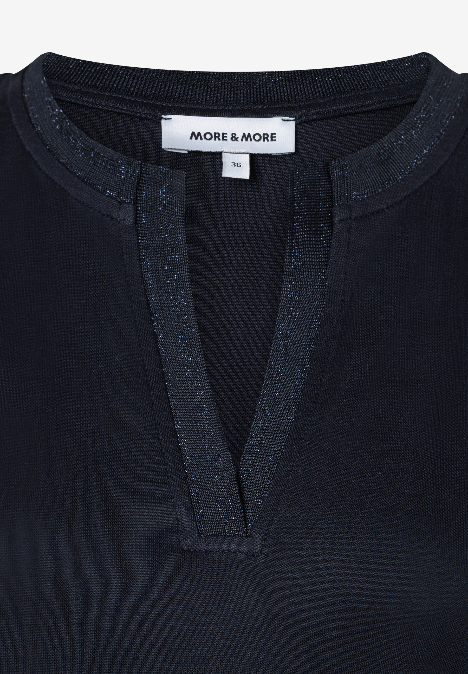 Nahaufnahme eines MORE & MORE Oberteils mit Jersey-Material und V-Ausschnitt. Nahaufnahme eines MORE & MORE Oberteils mit Jersey-Material und V-Ausschnitt.