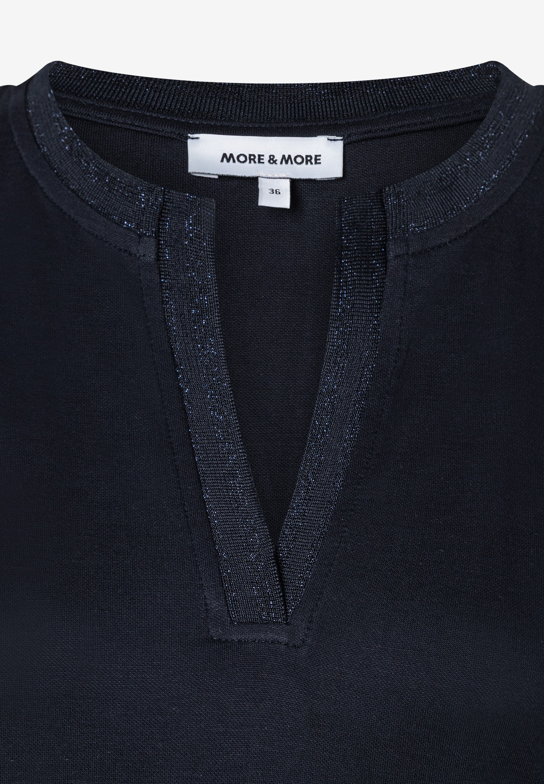 Nahaufnahme eines MORE & MORE Oberteils mit Jersey-Material und V-Ausschnitt. Nahaufnahme eines MORE & MORE Oberteils mit Jersey-Material und V-Ausschnitt.
