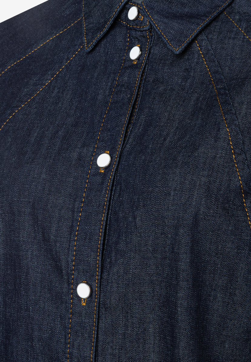 Nahaufnahme einer dunkelblauen MORE & MORE Bluse mit weißen Knöpfen und gelben Ziernähten. Nahaufnahme einer dunkelblauen MORE & MORE Bluse mit weißen Knöpfen und gelben Ziernähten.