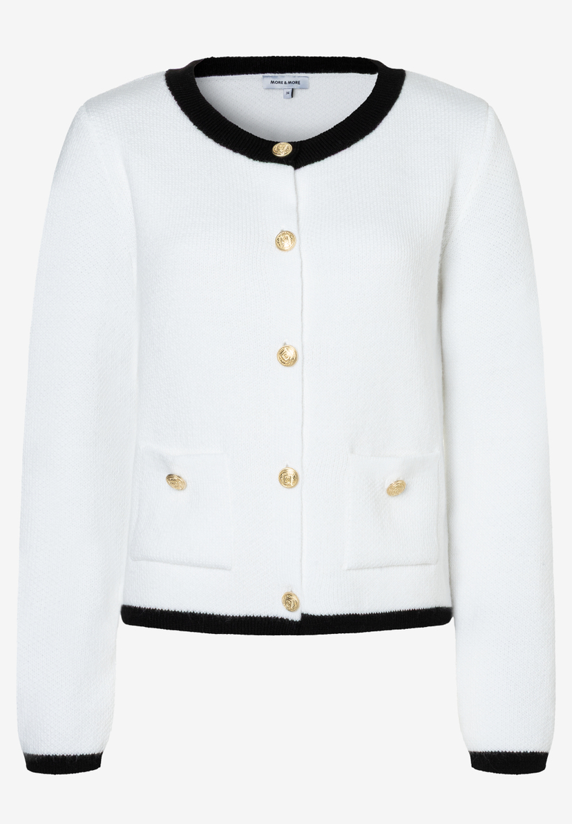 Eine weiße Strickjacke von MORE & MORE mit goldenen Knöpfen und schwarzen Abschlüssen. Eine weiße Strickjacke von MORE & MORE mit goldenen Knöpfen und schwarzen Abschlüssen.