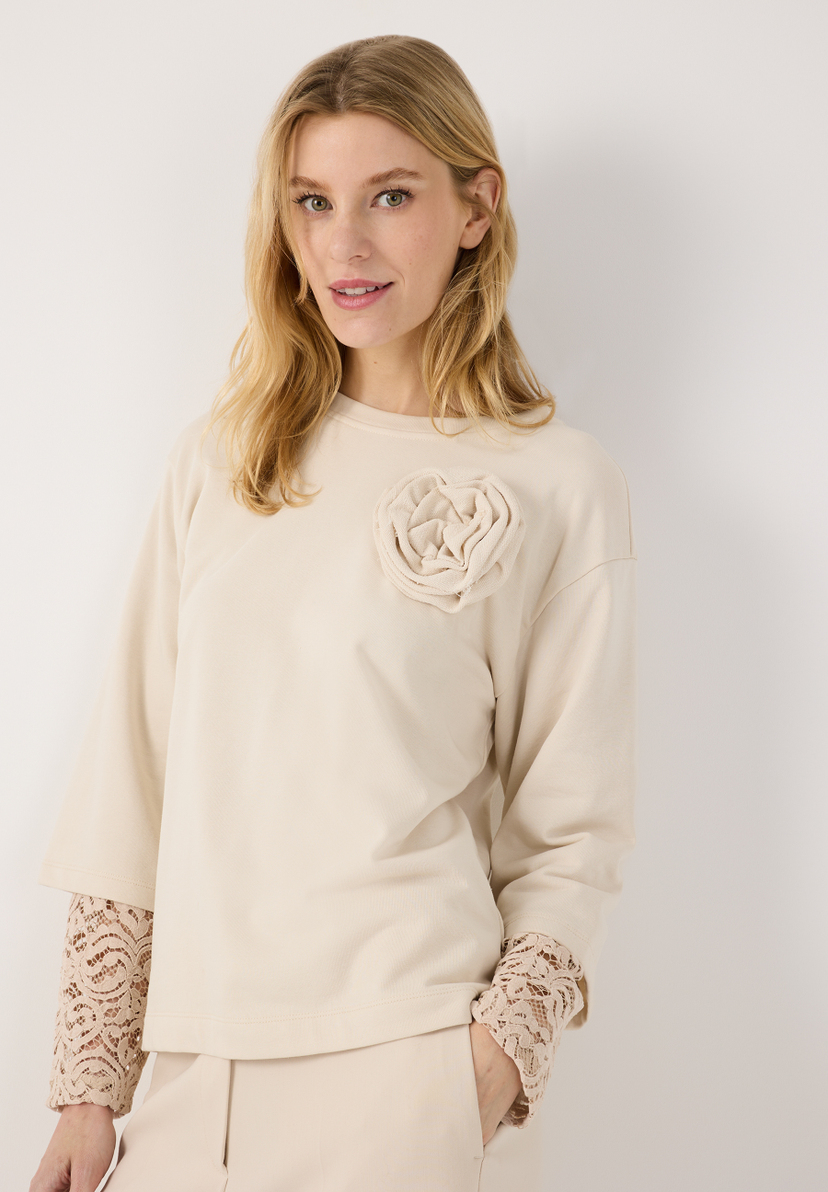 MORE & MORE Sweatshirt in Beige, verziert mit einer cremefarbenen Blütenapplikation auf der Brust und Spitzenmanschetten. MORE & MORE Sweatshirt in Beige, verziert mit einer cremefarbenen Blütenapplikation auf der Brust und Spitzenmanschetten.