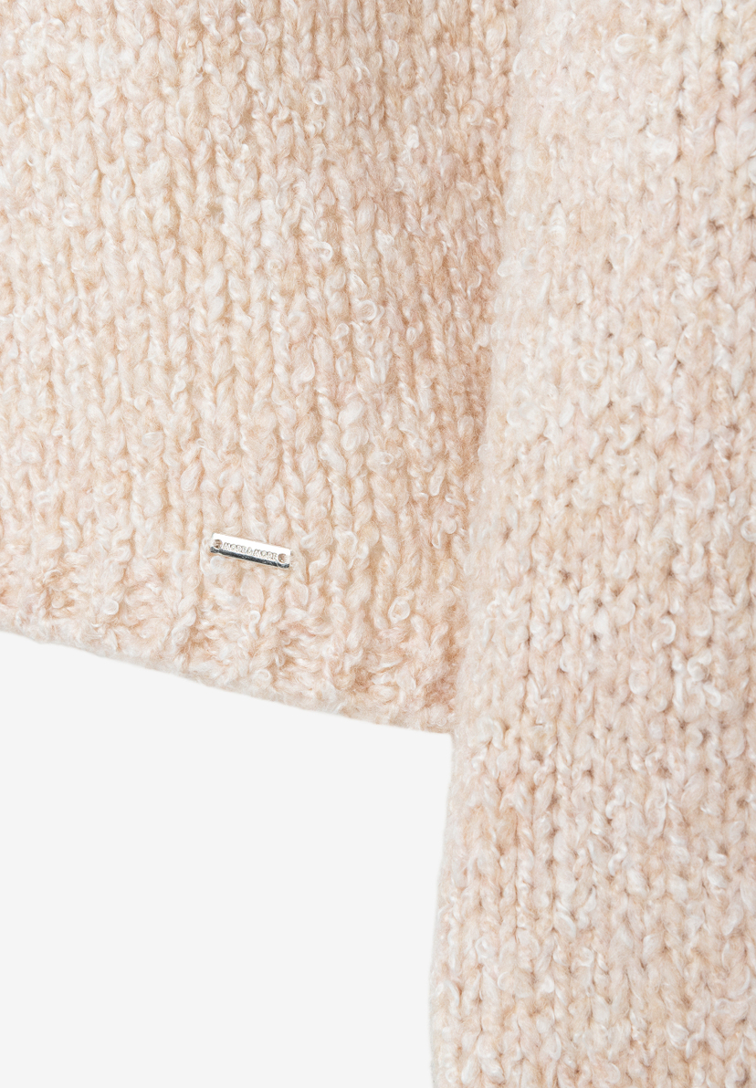 MORE & MORE Pullover & Strickware: Nahaufnahme eines beigen, locker gestrickten Stoffes mit feinen Schlaufen. Links eine kleine Metallschnalle mit der Aufschrift „MORE & MORE“. MORE & MORE Pullover & Strickware: Nahaufnahme eines beigen, locker gestrickten Stoffes mit feinen Schlaufen. Links eine kleine Metallschnalle mit der Aufschrift „MORE & MORE“.