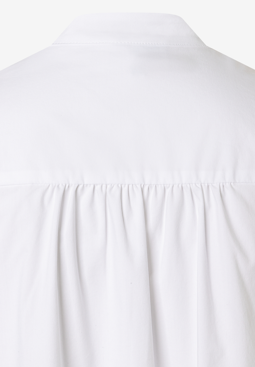 Detailansicht einer weißen MORE & MORE Bluse mit Falten unterhalb des Kragens. Detailansicht einer weißen MORE & MORE Bluse mit Falten unterhalb des Kragens.