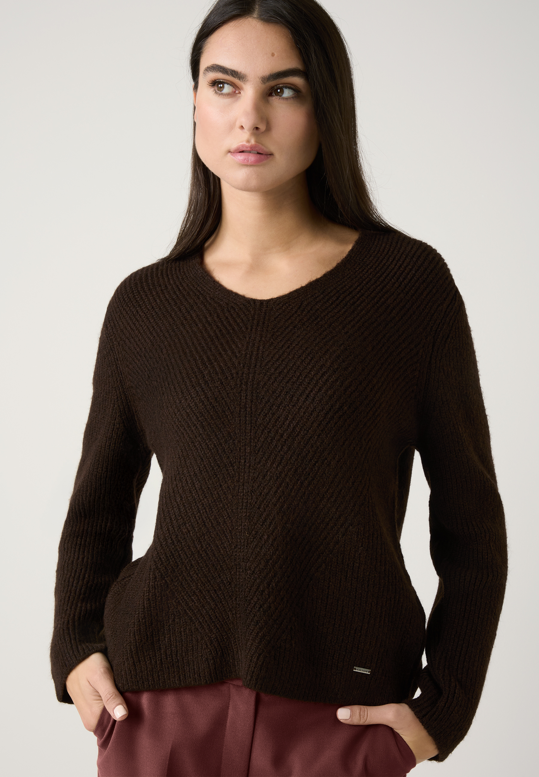 Eine Frau trägt ein Outfit von MORE & MORE: eine braune Jacke und weite, weinrote Hosen. Die Materialkonstruktion bietet angenehmen Tragekomfort. Eine Frau trägt ein Outfit von MORE & MORE: eine braune Jacke und weite, weinrote Hosen. Die Materialkonstruktion bietet angenehmen Tragekomfort.