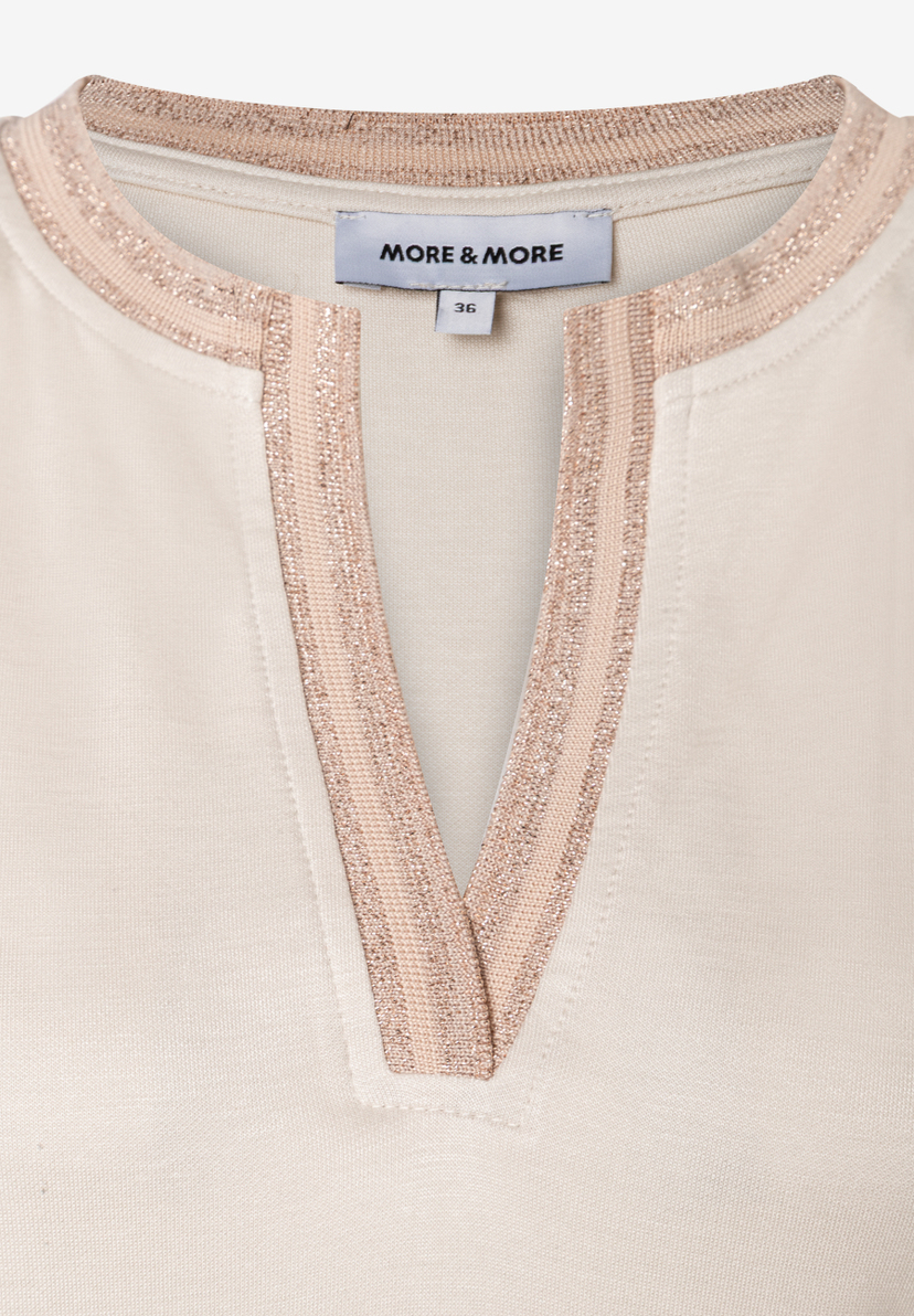 Detailansicht eines MORE & MORE Oberteils mit Jersey-Struktur und V-Ausschnitt mit Glitzer-Details. Detailansicht eines MORE & MORE Oberteils mit Jersey-Struktur und V-Ausschnitt mit Glitzer-Details.