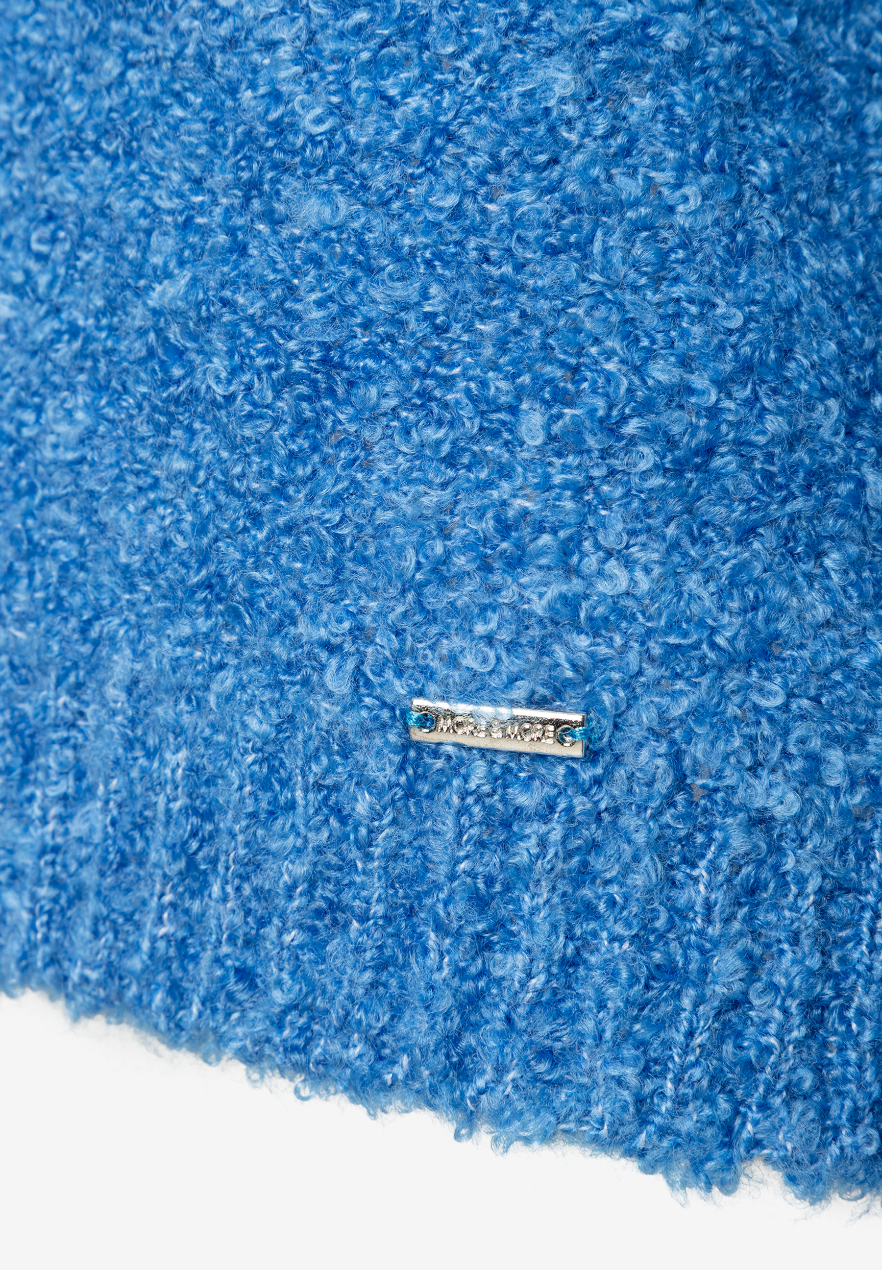 Nahaufnahme eines blauen MORE & MORE Bouclé-Oberteils mit Logo-Schild, das einen angenehmen Tragekomfort verspricht. Nahaufnahme eines blauen MORE & MORE Bouclé-Oberteils mit Logo-Schild, das einen angenehmen Tragekomfort verspricht.