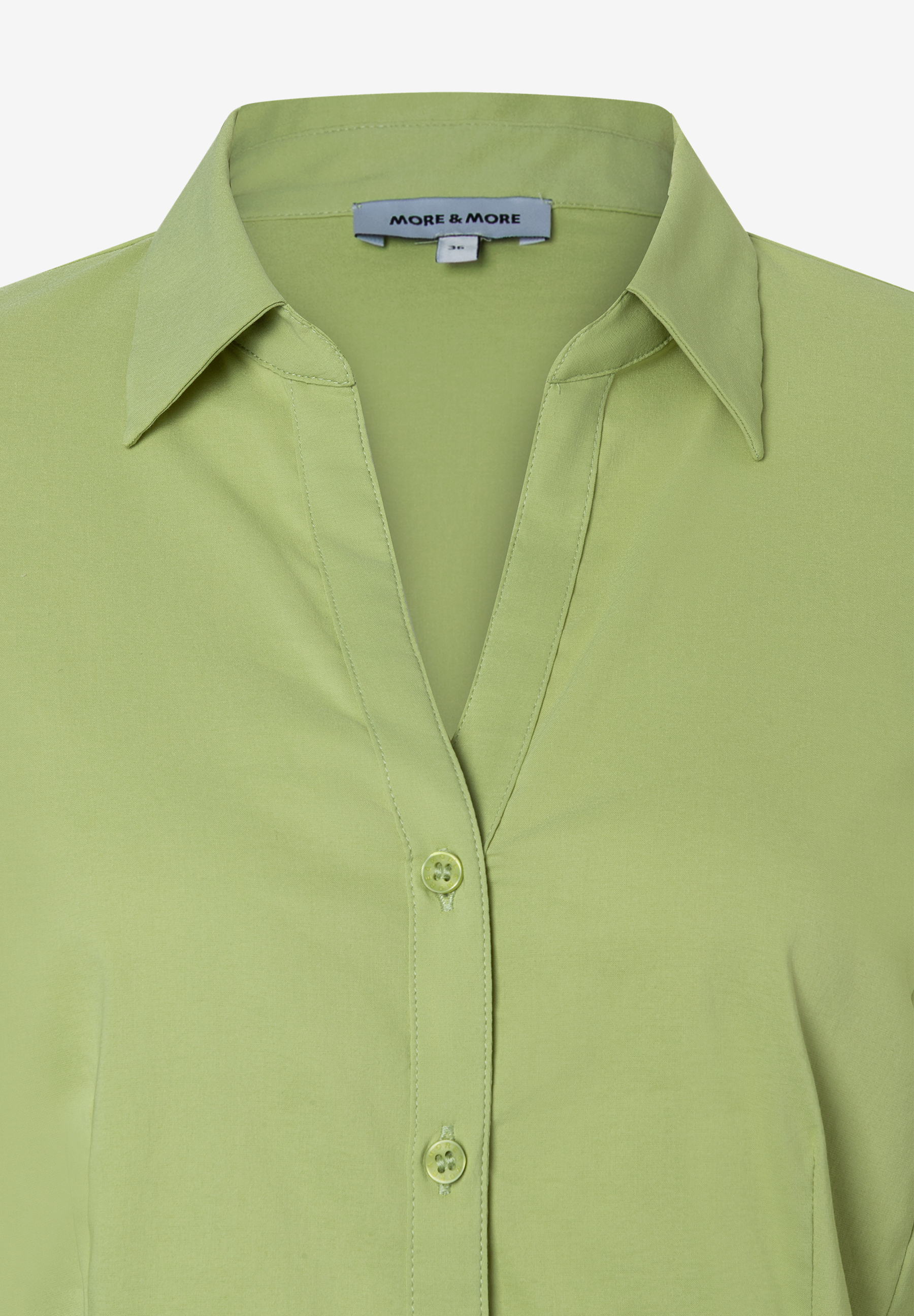 Nahaufnahme einer hellgrünen MORE & MORE Bluse aus Popeline mit Kragen und Knopfleiste. Nahaufnahme einer hellgrünen MORE & MORE Bluse aus Popeline mit Kragen und Knopfleiste.