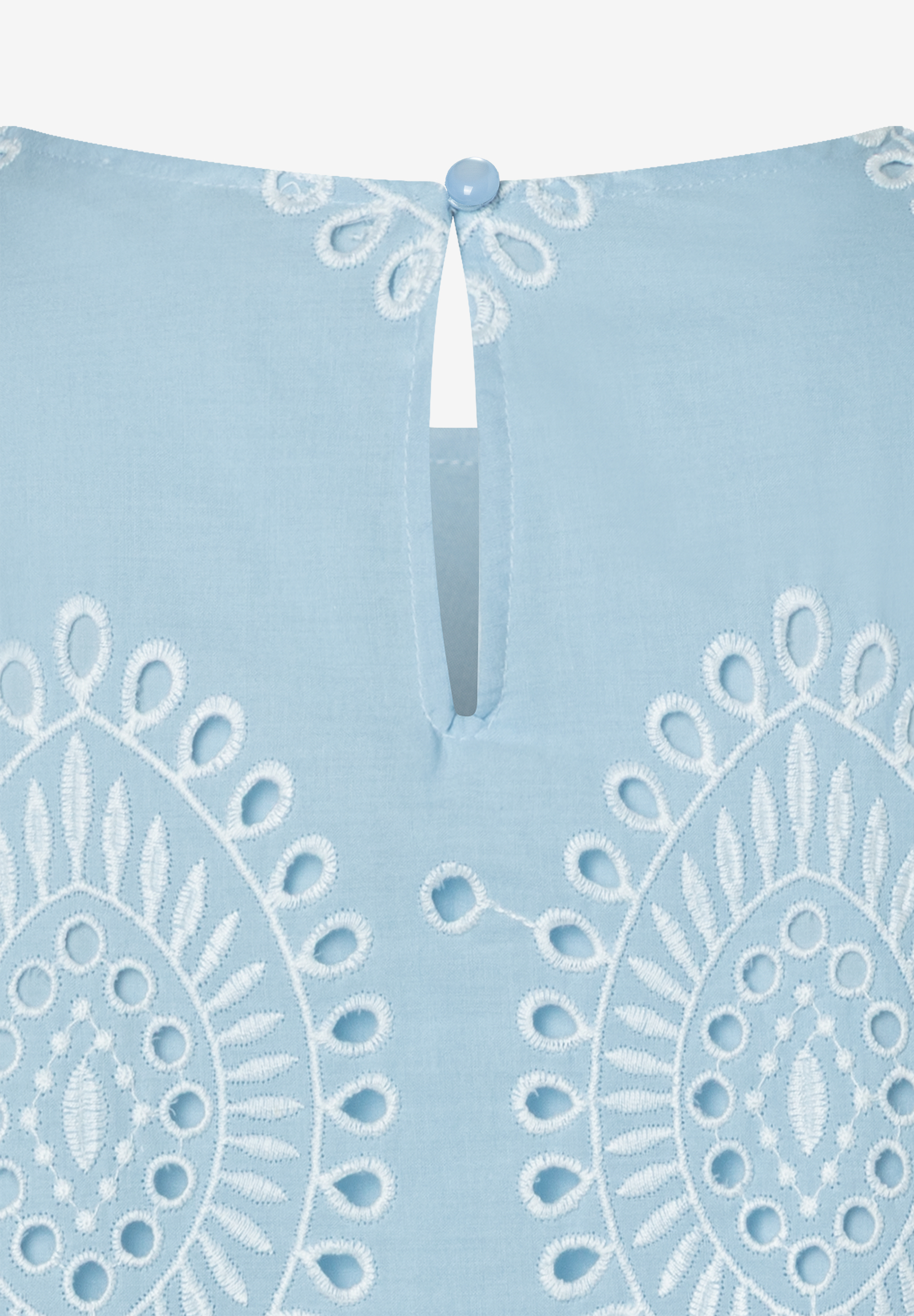 Nahaufnahme einer MORE & MORE Bluse mit feiner, weißer Spitze auf hellblauem Stoff und einem Knopfverschluss im Nacken. Nahaufnahme einer MORE & MORE Bluse mit feiner, weißer Spitze auf hellblauem Stoff und einem Knopfverschluss im Nacken.