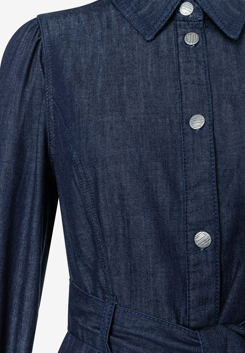 Nahaufnahme eines MORE & MORE Oberteils aus Denim mit Knöpfen und langen Ärmeln. Nahaufnahme eines MORE & MORE Oberteils aus Denim mit Knöpfen und langen Ärmeln.