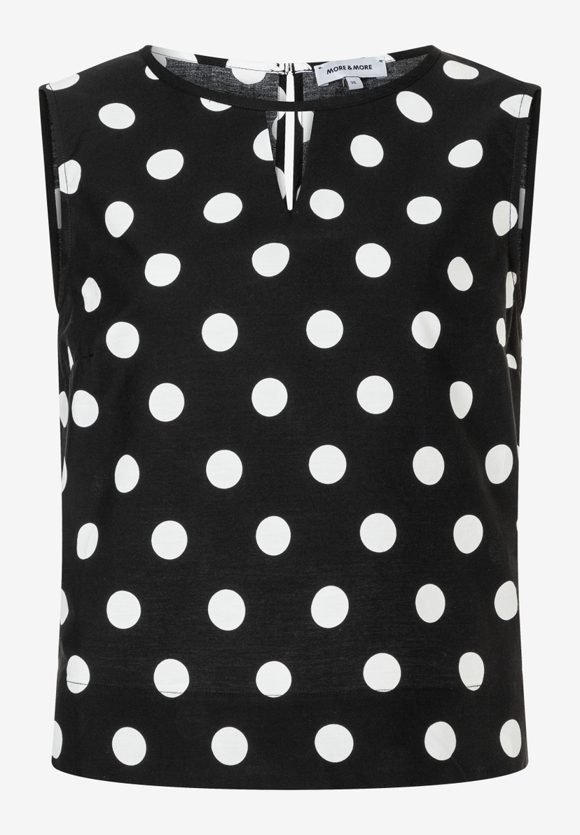 Eine ärmellose MORE & MORE Bluse mit weißen Punkten auf schwarzem Stoff. Eine ärmellose MORE & MORE Bluse mit weißen Punkten auf schwarzem Stoff.
