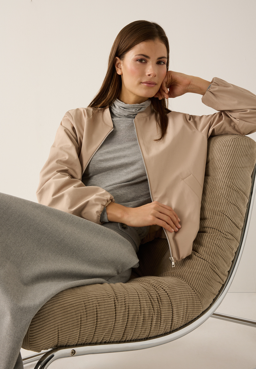 Eine Frau sitzt in einem Stuhl und trägt einen MORE & MORE Blazer aus Webware. Sie lehnt ihren Kopf an ihre Hand. Eine Frau sitzt in einem Stuhl und trägt einen MORE & MORE Blazer aus Webware. Sie lehnt ihren Kopf an ihre Hand.