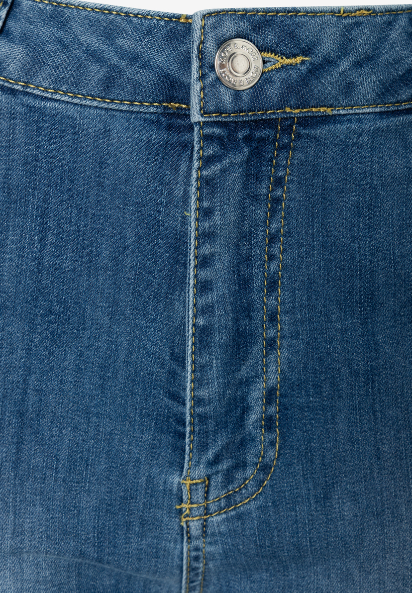 MORE & MORE Blue Jeans Detail: Nahaufnahme des Knopfverschlusses mit Markenprägung und gelben Nähten auf blauem Denim.