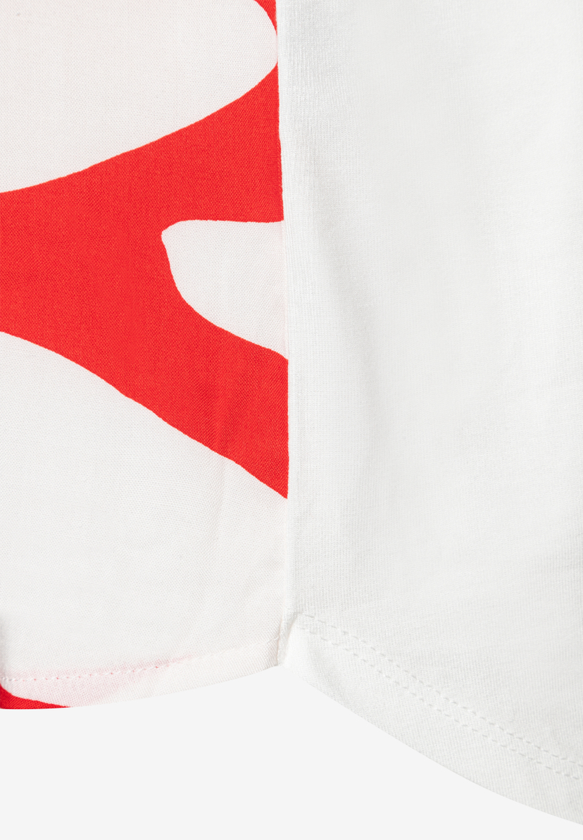 Nahaufnahme eines MORE & MORE Oberteils mit rotem Muster auf weißem Grund. Nahaufnahme eines MORE & MORE Oberteils mit rotem Muster auf weißem Grund.