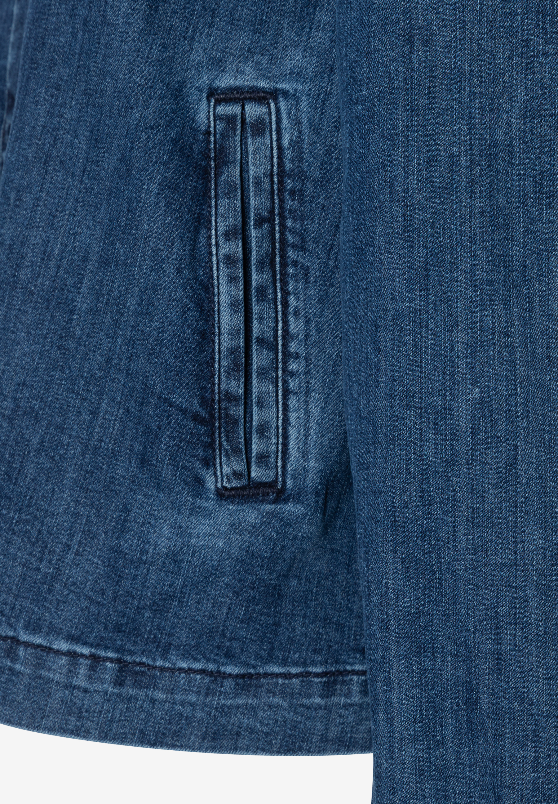 Nahaufnahme eines blauen MORE & MORE Blasers aus Denimstoff mit einer kleinen Tasche. Nahaufnahme eines blauen MORE & MORE Blasers aus Denimstoff mit einer kleinen Tasche.