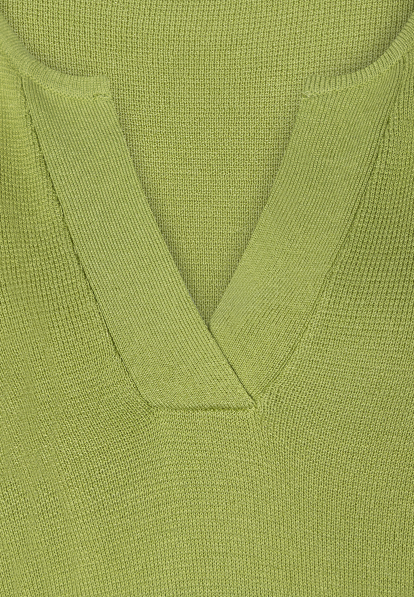 Nahaufnahme eines lindgrünen MORE & MORE Strickpullovers mit V-Ausschnitt. Nahaufnahme eines lindgrünen MORE & MORE Strickpullovers mit V-Ausschnitt.
