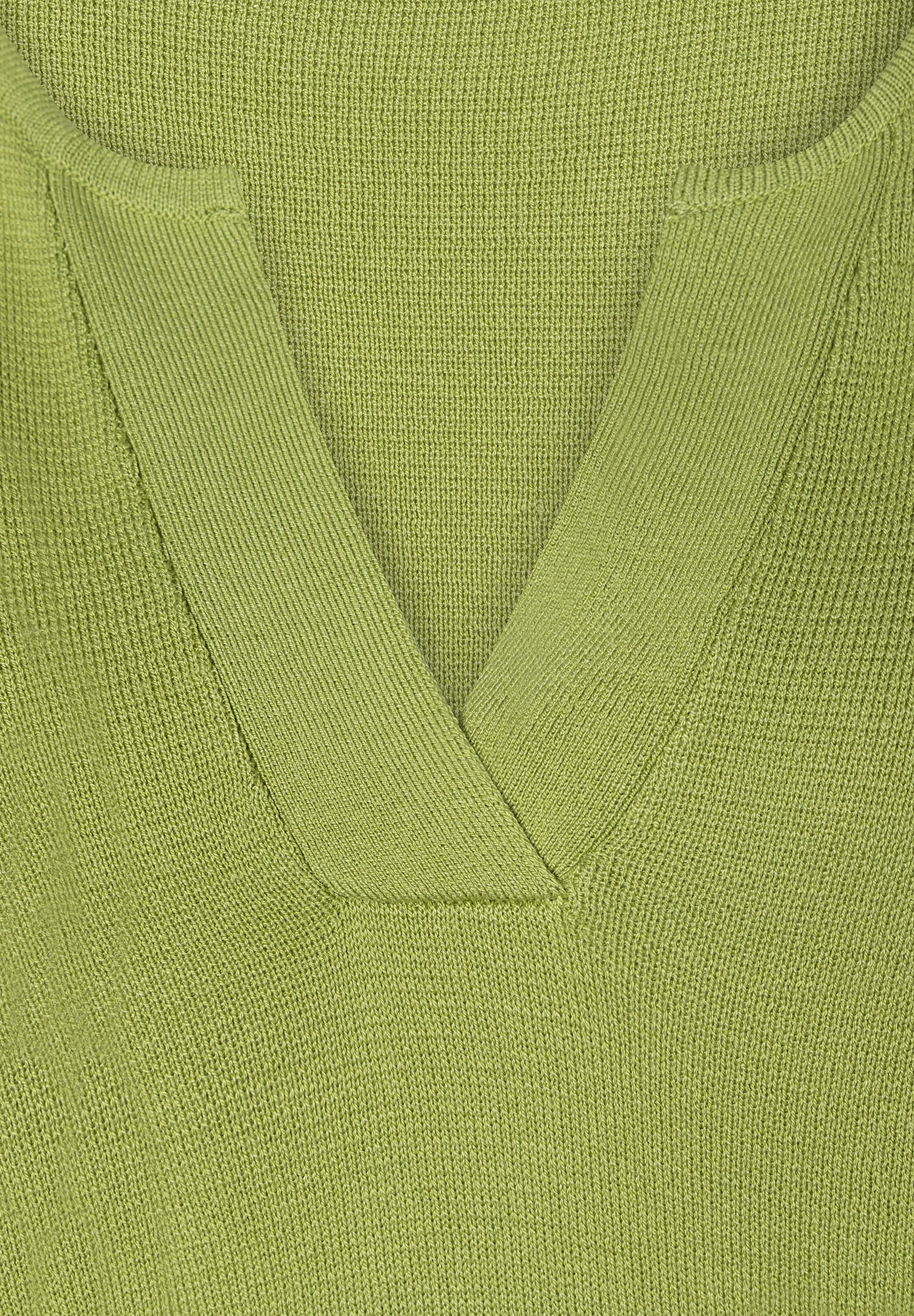 Nahaufnahme eines lindgrünen MORE & MORE Strickpullovers mit V-Ausschnitt. Nahaufnahme eines lindgrünen MORE & MORE Strickpullovers mit V-Ausschnitt.