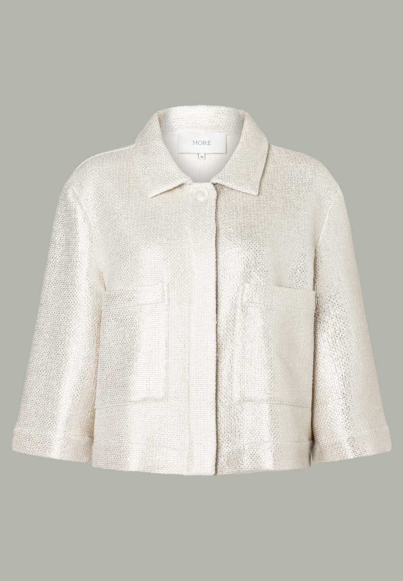 Eine beige MORE & MORE Jacke mit Knöpfen, Kragen und kurzen Ärmeln vor grauem Hintergrund. Eine beige MORE & MORE Jacke mit Knöpfen, Kragen und kurzen Ärmeln vor grauem Hintergrund.