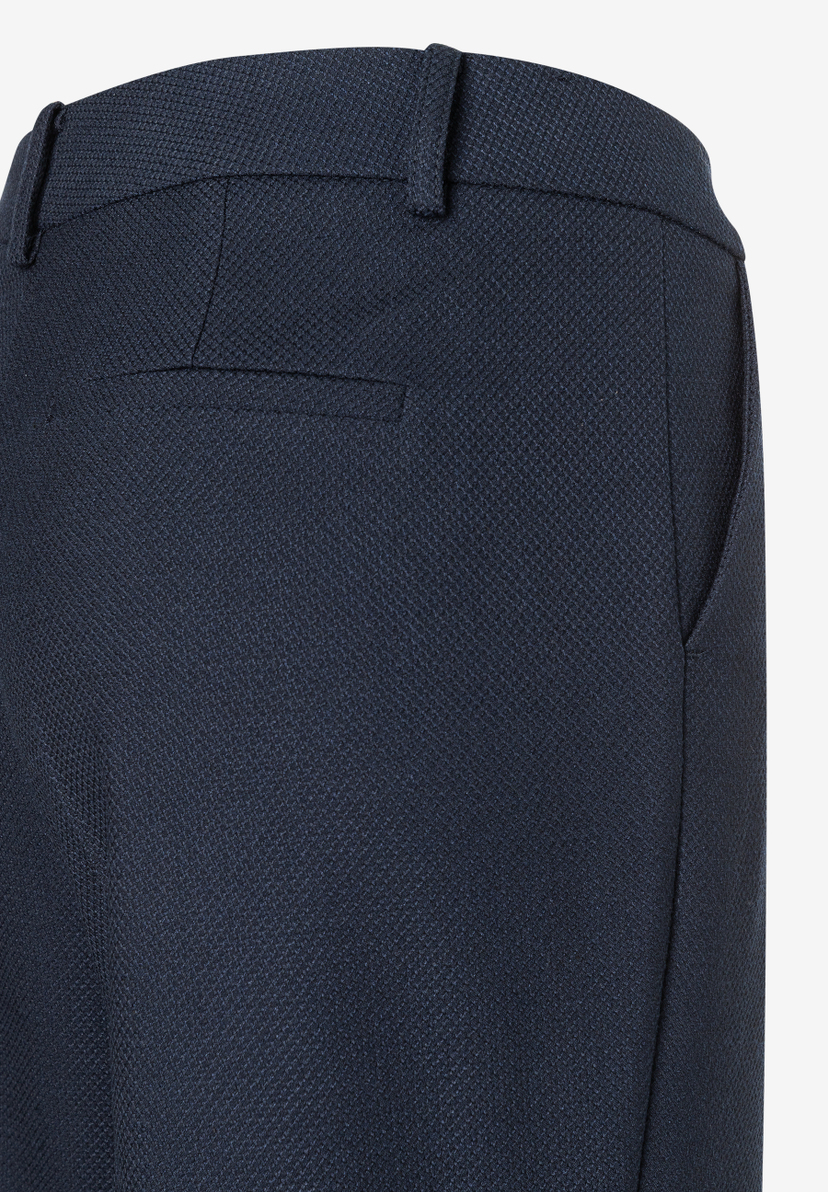 Detailaufnahme einer MORE & MORE Hose mit dunklem, strukturiertem Stoff, Tascheneingriff und Gürtelschlaufen. Detailaufnahme einer MORE & MORE Hose mit dunklem, strukturiertem Stoff, Tascheneingriff und Gürtelschlaufen.