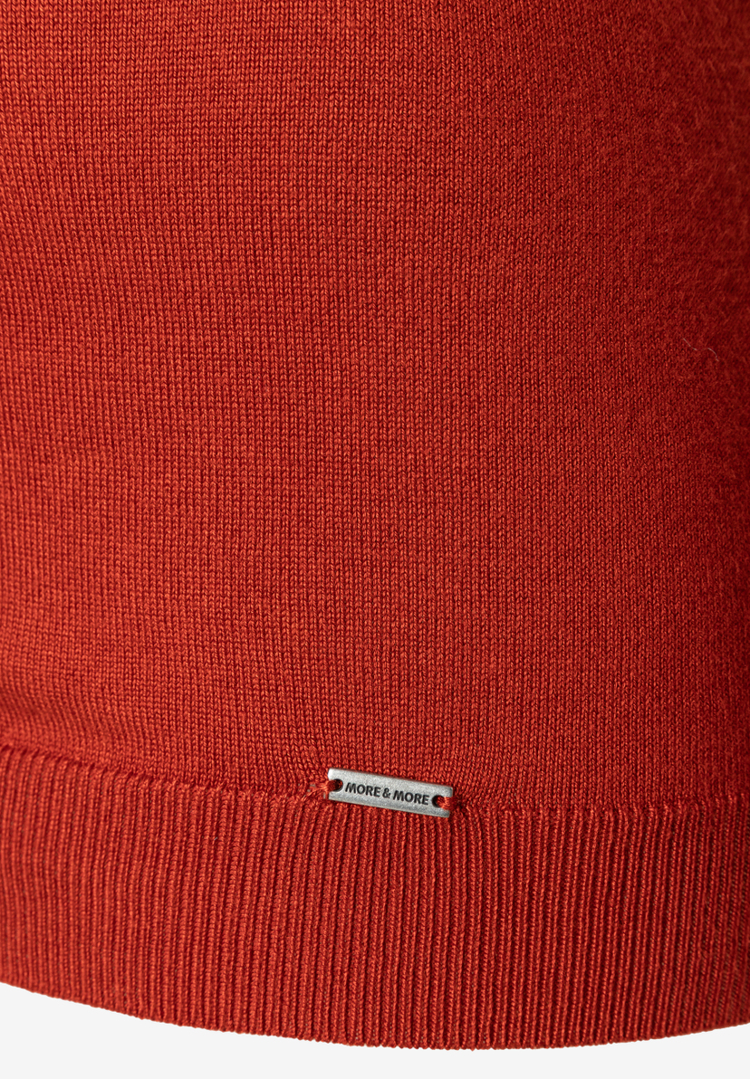 Nahaufnahme eines MORE & MORE Oberteils aus Feinstrick mit Logo-Detail. Nahaufnahme eines MORE & MORE Oberteils aus Feinstrick mit Logo-Detail.