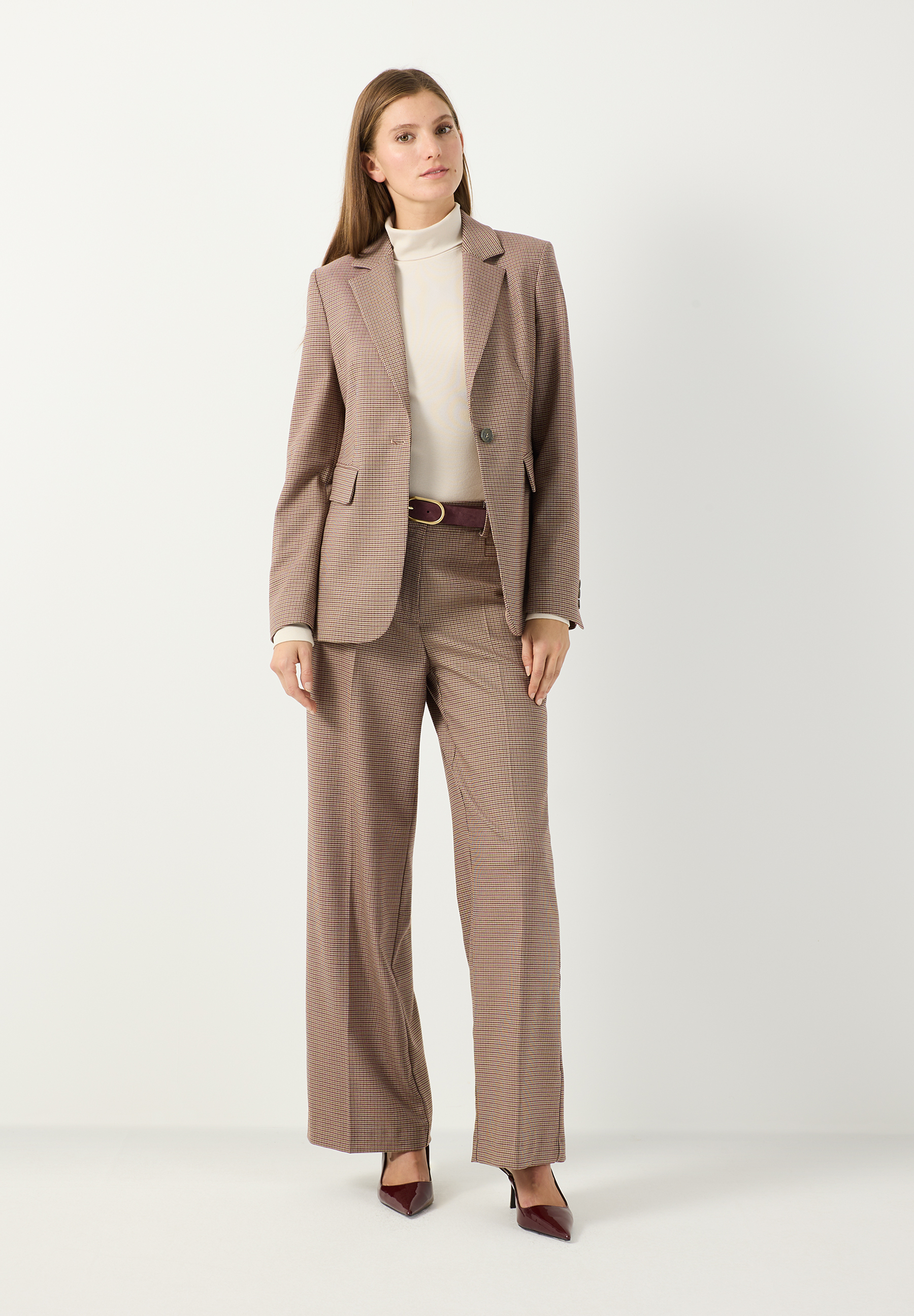 MORE & MORE geripptes Langarmshirt in Beige, von einer Frau unter einem braunen Blazer mit Anzughose und High Heels getragen.