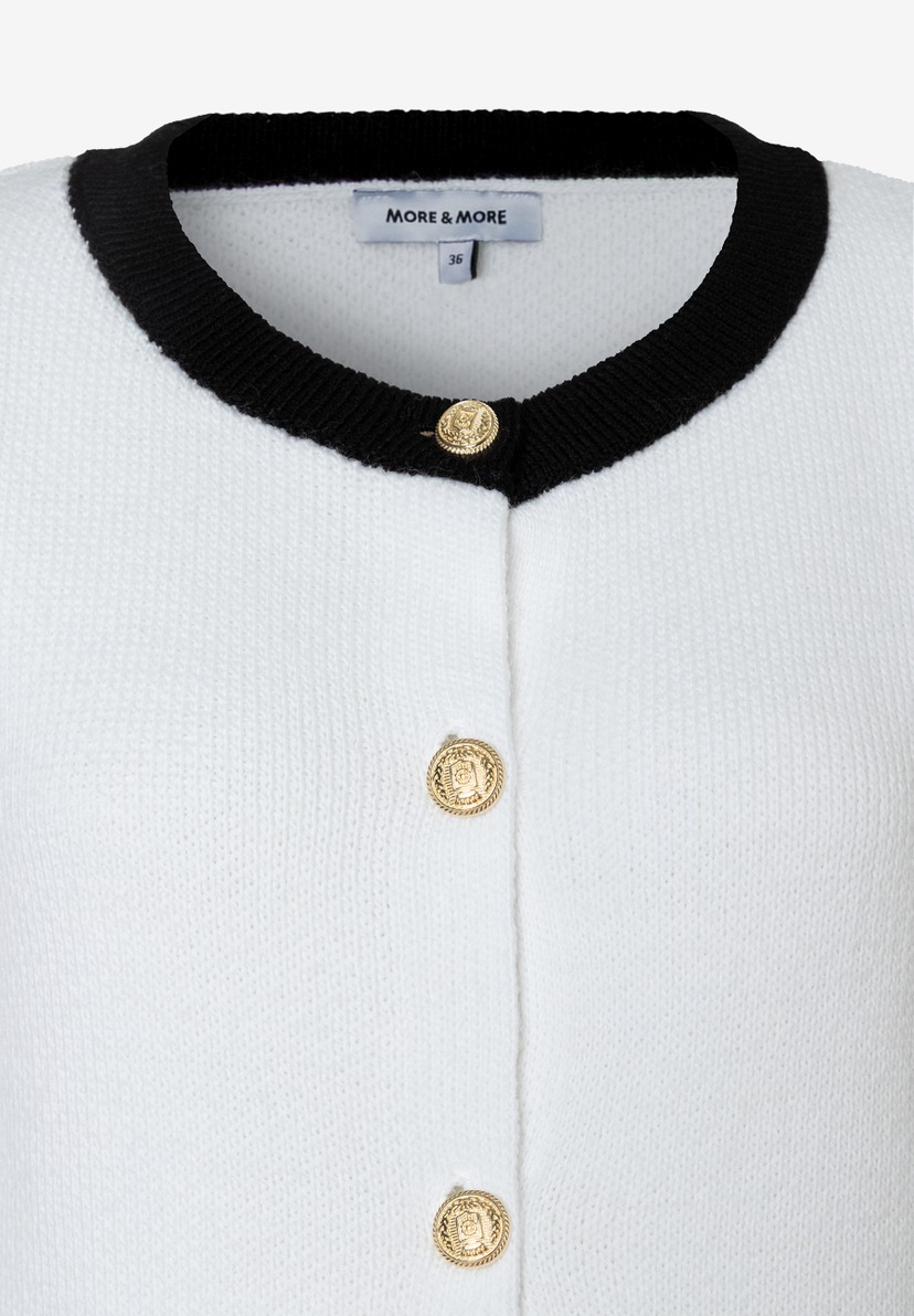 Detailansicht eines MORE & MORE Oberteils/Strickjacke in Weiß mit schwarzen Akzenten und goldenen Knöpfen. Detailansicht eines MORE & MORE Oberteils/Strickjacke in Weiß mit schwarzen Akzenten und goldenen Knöpfen.