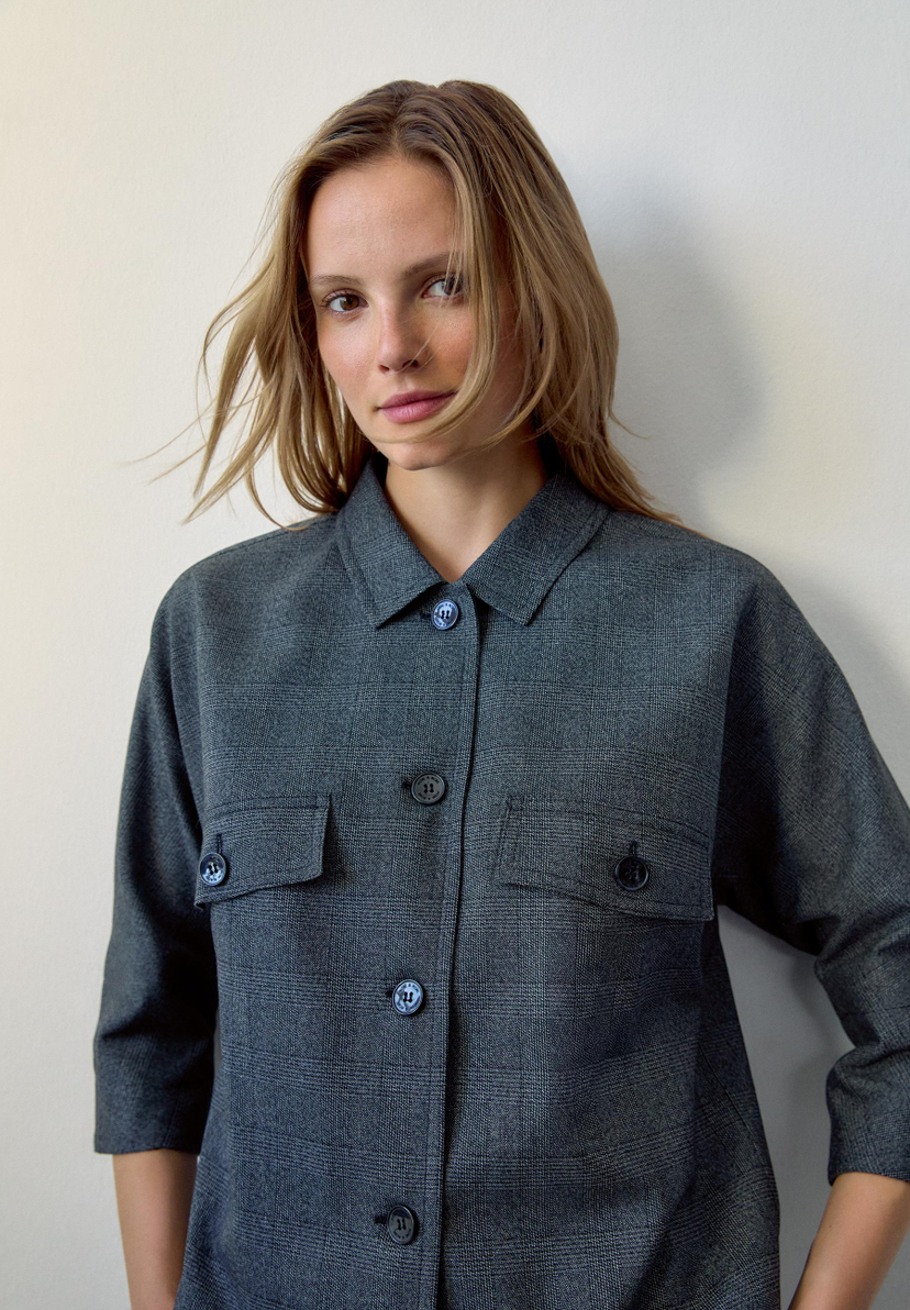 Eine Frau mit blonden Haaren trägt einen grauen MORE & MORE Blazer mit Webware und angenehmen Tragekomfort vor einer weißen Wand. Eine Frau mit blonden Haaren trägt einen grauen MORE & MORE Blazer mit Webware und angenehmen Tragekomfort vor einer weißen Wand.