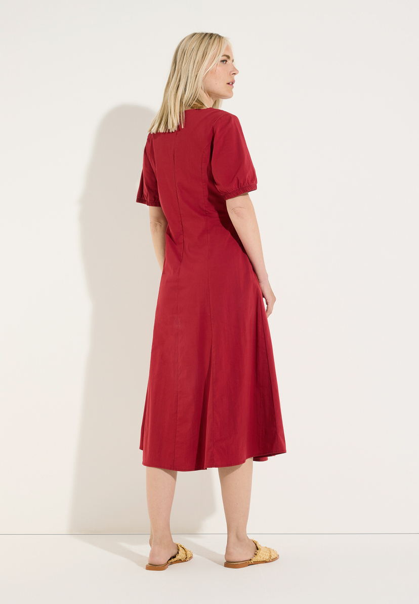 MORE & MORE rotes Kleid, ein blondes Model präsentiert das Kleid auf einem weißen Hintergrund, Seitenansicht. MORE & MORE rotes Kleid, ein blondes Model präsentiert das Kleid auf einem weißen Hintergrund, Seitenansicht.