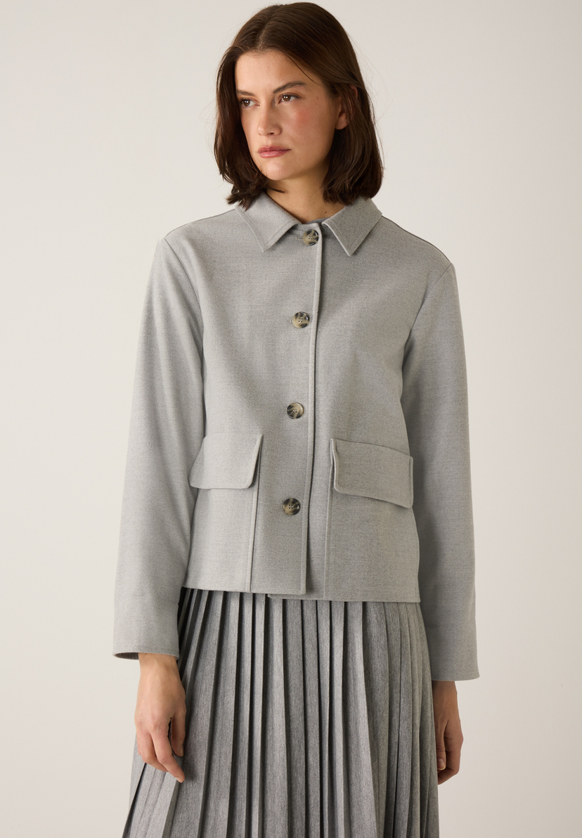 Eine Frau trägt einen grauen MORE & MORE Blazer mit Taschen und Knöpfen. Eine Frau trägt einen grauen MORE & MORE Blazer mit Taschen und Knöpfen.