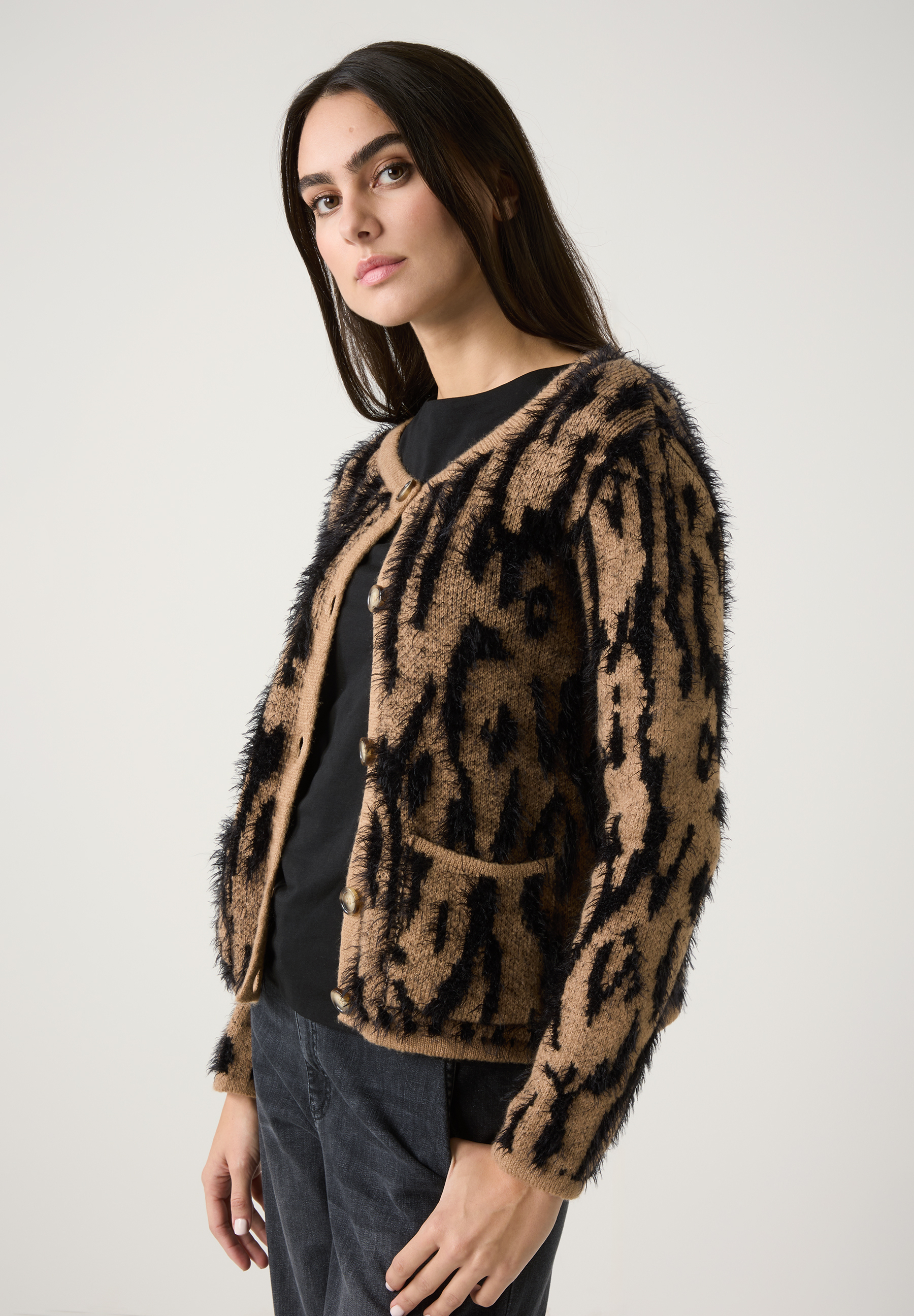Eine Frau trägt eine Strickjacke von MORE & MORE mit Leopardenmuster. Die Materialkonstruktion ist wärmend und elastisch.