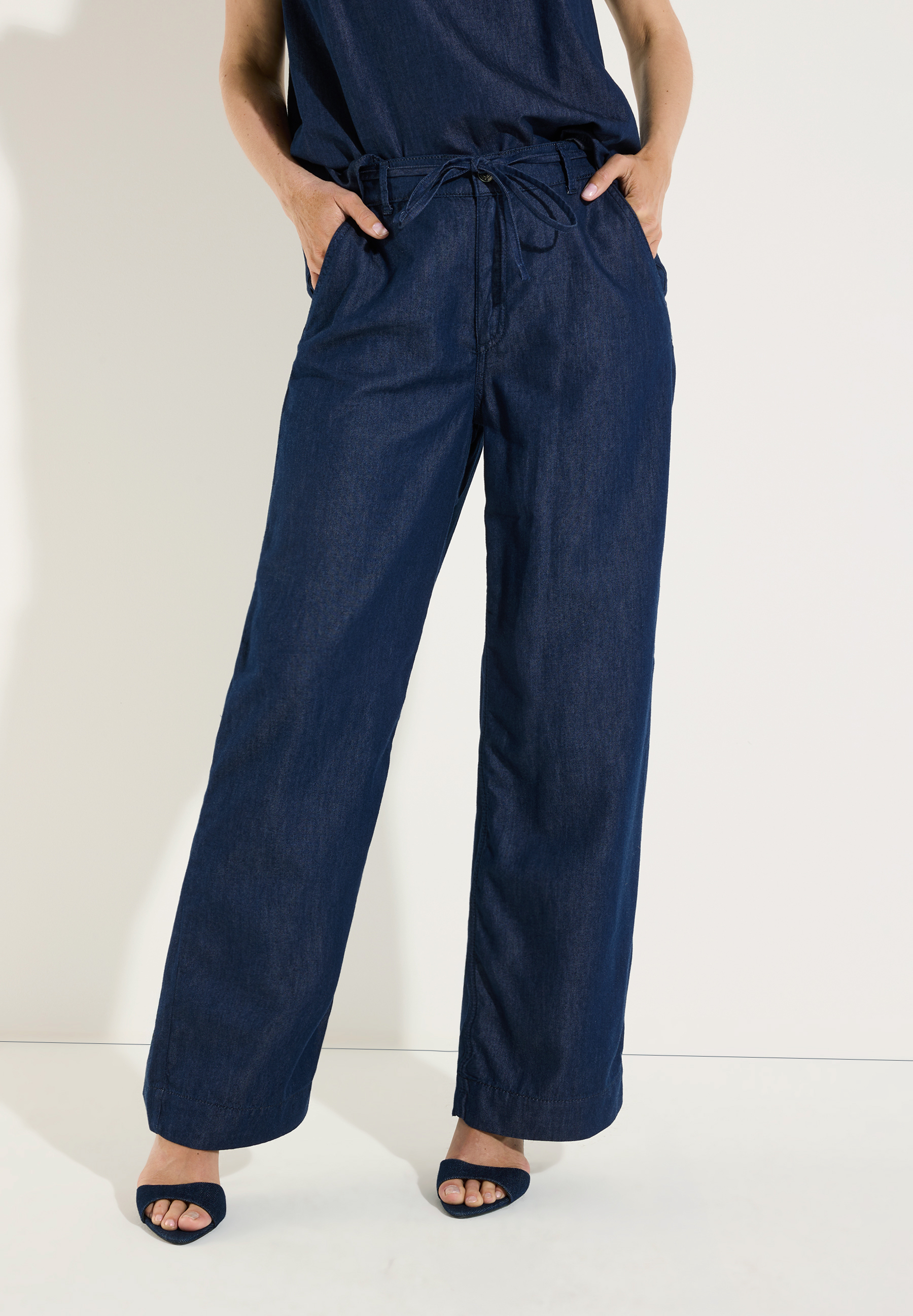 MORE & MORE Jeans: eine Person trägt eine dunkle Jeans mit weitem Bein und Kordelzug auf weißem Hintergrund. MORE & MORE Jeans: eine Person trägt eine dunkle Jeans mit weitem Bein und Kordelzug auf weißem Hintergrund.