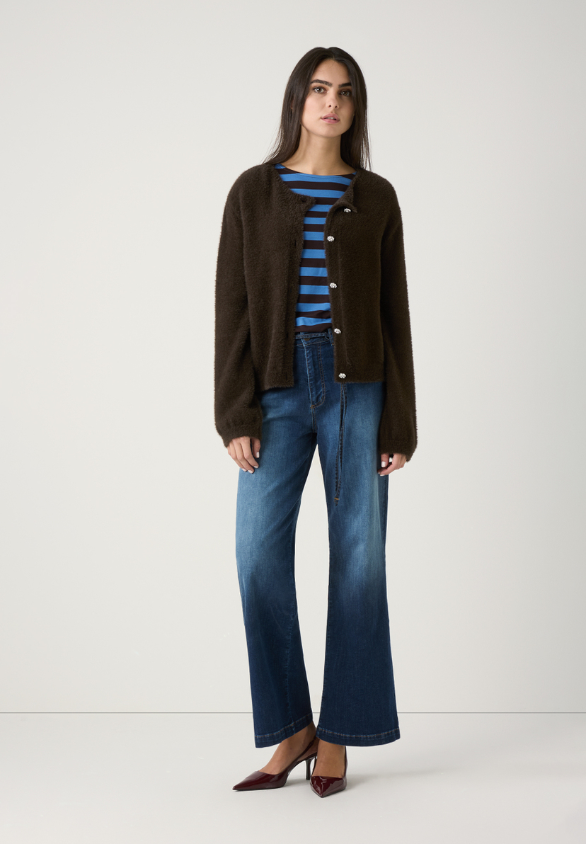 Eine Frau in MORE & MORE Strickware, Jeans und Slingpumps vor hellem Hintergrund. Eine Frau in MORE & MORE Strickware, Jeans und Slingpumps vor hellem Hintergrund.