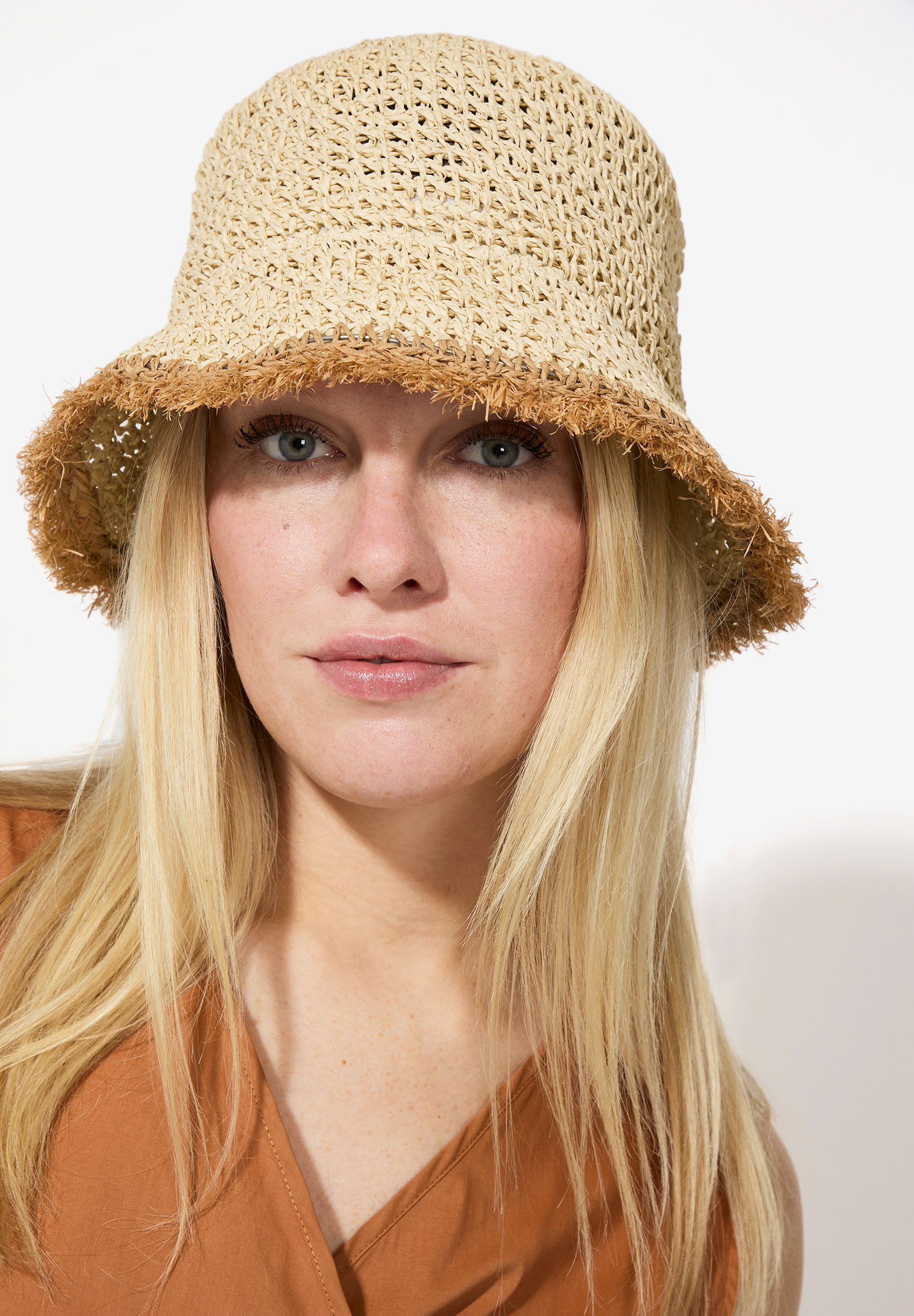 Nahaufnahme einer Frau mit blonden Haaren und einem MORE & MORE Hut aus Stroh. Nahaufnahme einer Frau mit blonden Haaren und einem MORE & MORE Hut aus Stroh.