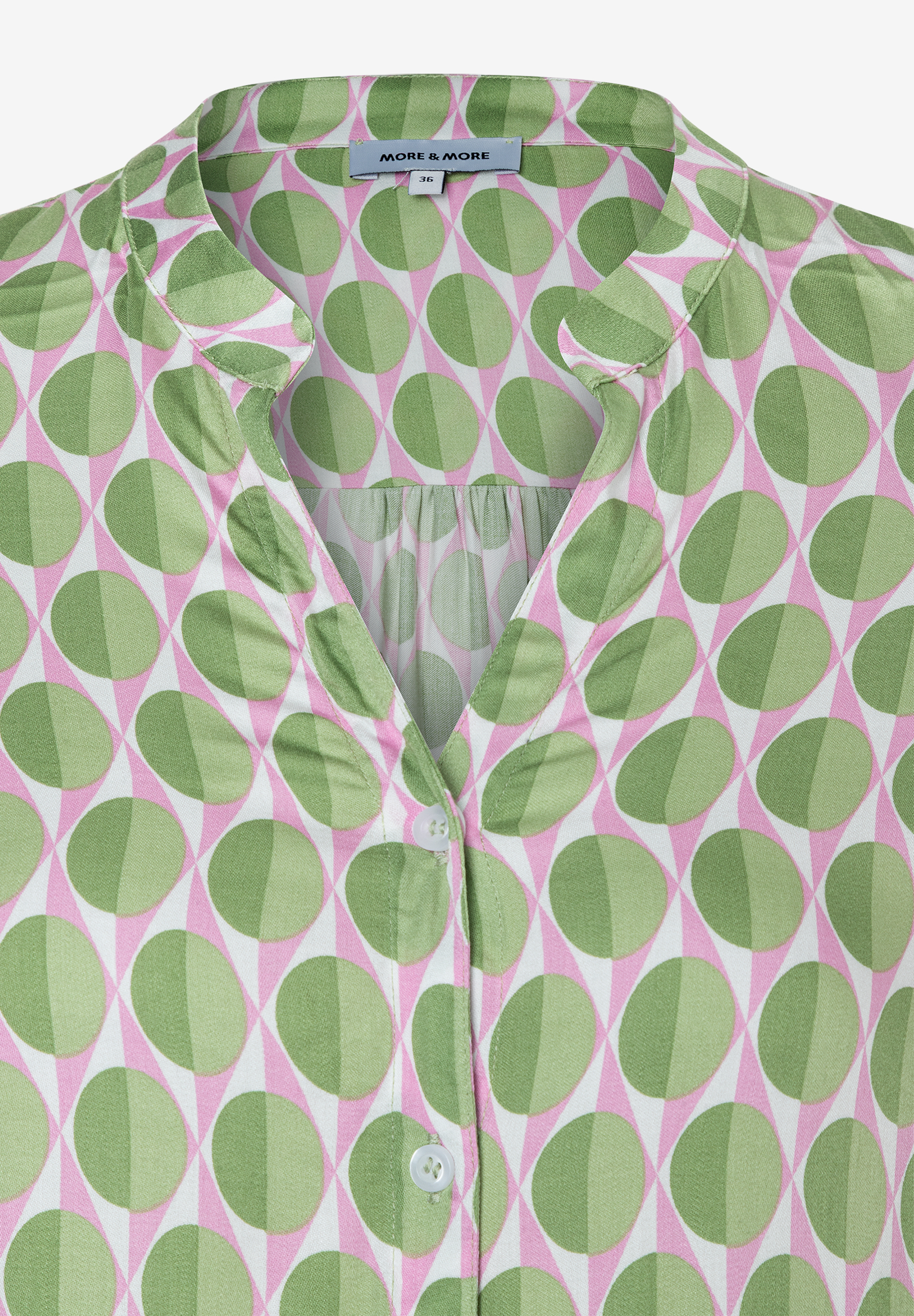 Detailansicht einer MORE & MORE Bluse mit grün-rosa Muster und Knopfleiste. Detailansicht einer MORE & MORE Bluse mit grün-rosa Muster und Knopfleiste.