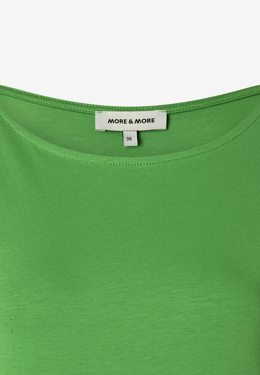 Nahaufnahme eines grünen MORE & MORE-Tops mit Jersey-Material und Größenetikett. Nahaufnahme eines grünen MORE & MORE-Tops mit Jersey-Material und Größenetikett.