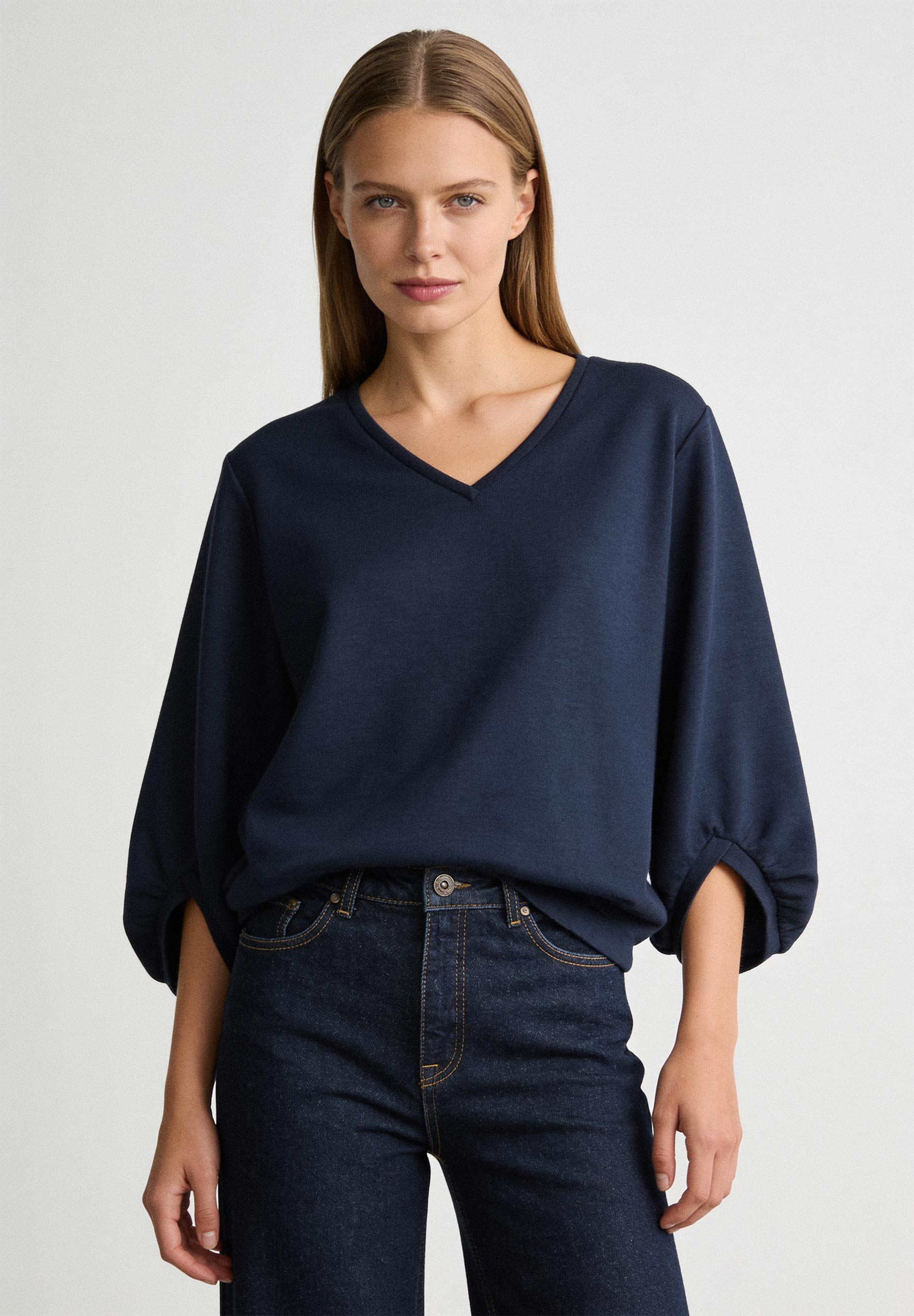 AI generated - MORE & MORE Sweatshirt: Eine Frau trägt ein dunkelblaues Sweatshirt mit V-Ausschnitt & 3/4-Ärmeln, kombiniert mit dunkler Jeans.
