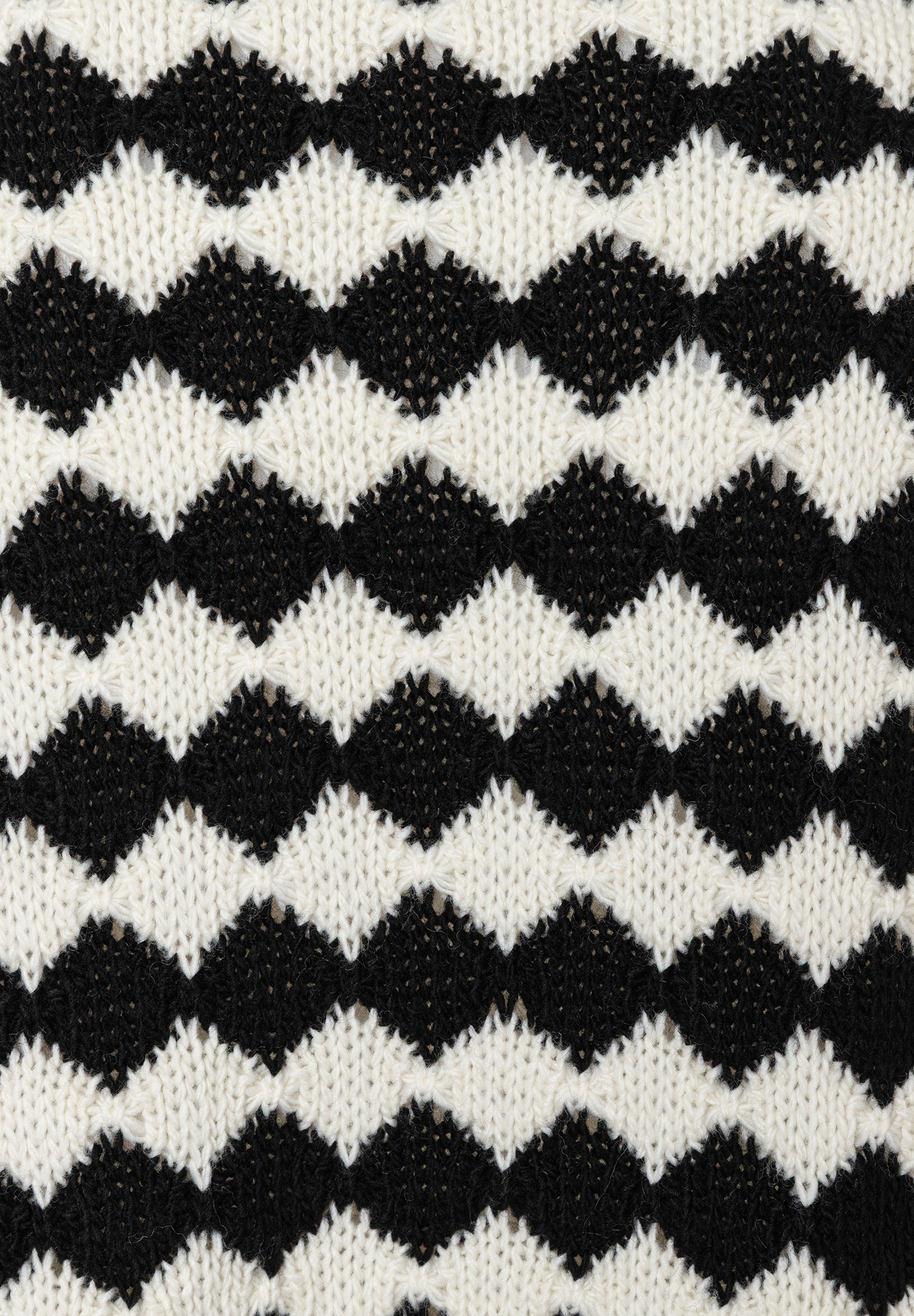 Detailaufnahme von MORE & MORE Strickware in Schwarz und Weiß mit Rautenmuster. Detailaufnahme von MORE & MORE Strickware in Schwarz und Weiß mit Rautenmuster.