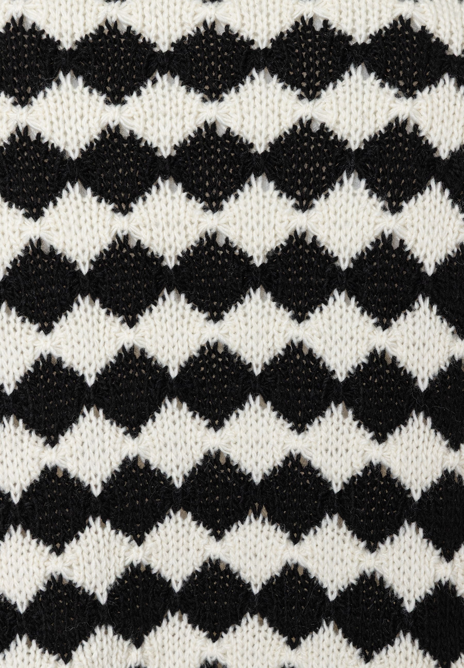 Detailaufnahme von MORE & MORE Strickware in Schwarz und Weiß mit Rautenmuster. Detailaufnahme von MORE & MORE Strickware in Schwarz und Weiß mit Rautenmuster.