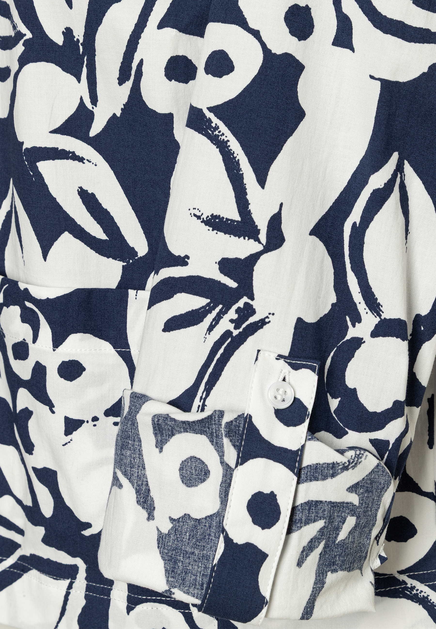 Nahaufnahme einer MORE & MORE Bluse mit blau-weißem Blumenmuster, Manschette und Knopf sichtbar. Nahaufnahme einer MORE & MORE Bluse mit blau-weißem Blumenmuster, Manschette und Knopf sichtbar.
