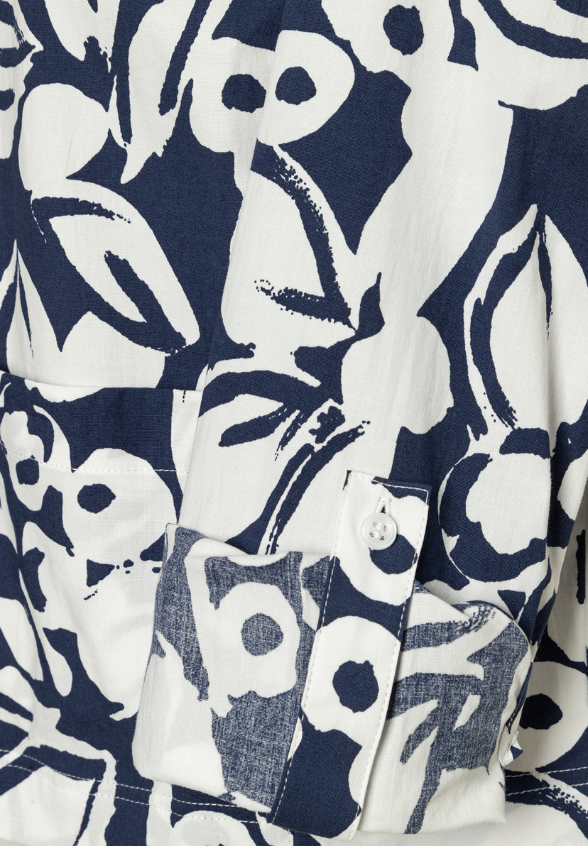 Nahaufnahme einer MORE & MORE Bluse mit blau-weißem Blumenmuster, Manschette und Knopf sichtbar. Nahaufnahme einer MORE & MORE Bluse mit blau-weißem Blumenmuster, Manschette und Knopf sichtbar.