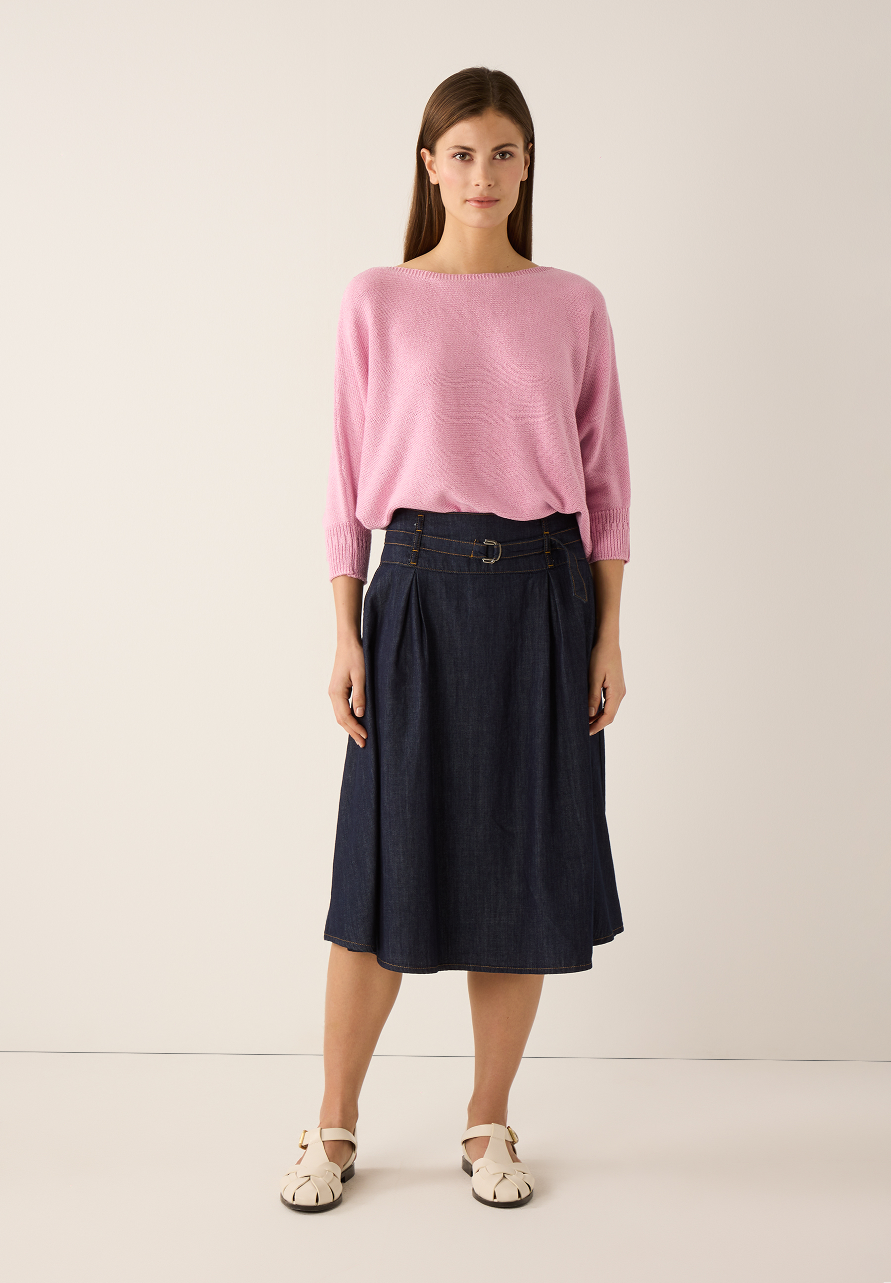 Eine Frau in einem MORE & MORE Pullover und Rock, der eine modische Silhouette erzeugt. Eine Frau in einem MORE & MORE Pullover und Rock, der eine modische Silhouette erzeugt.