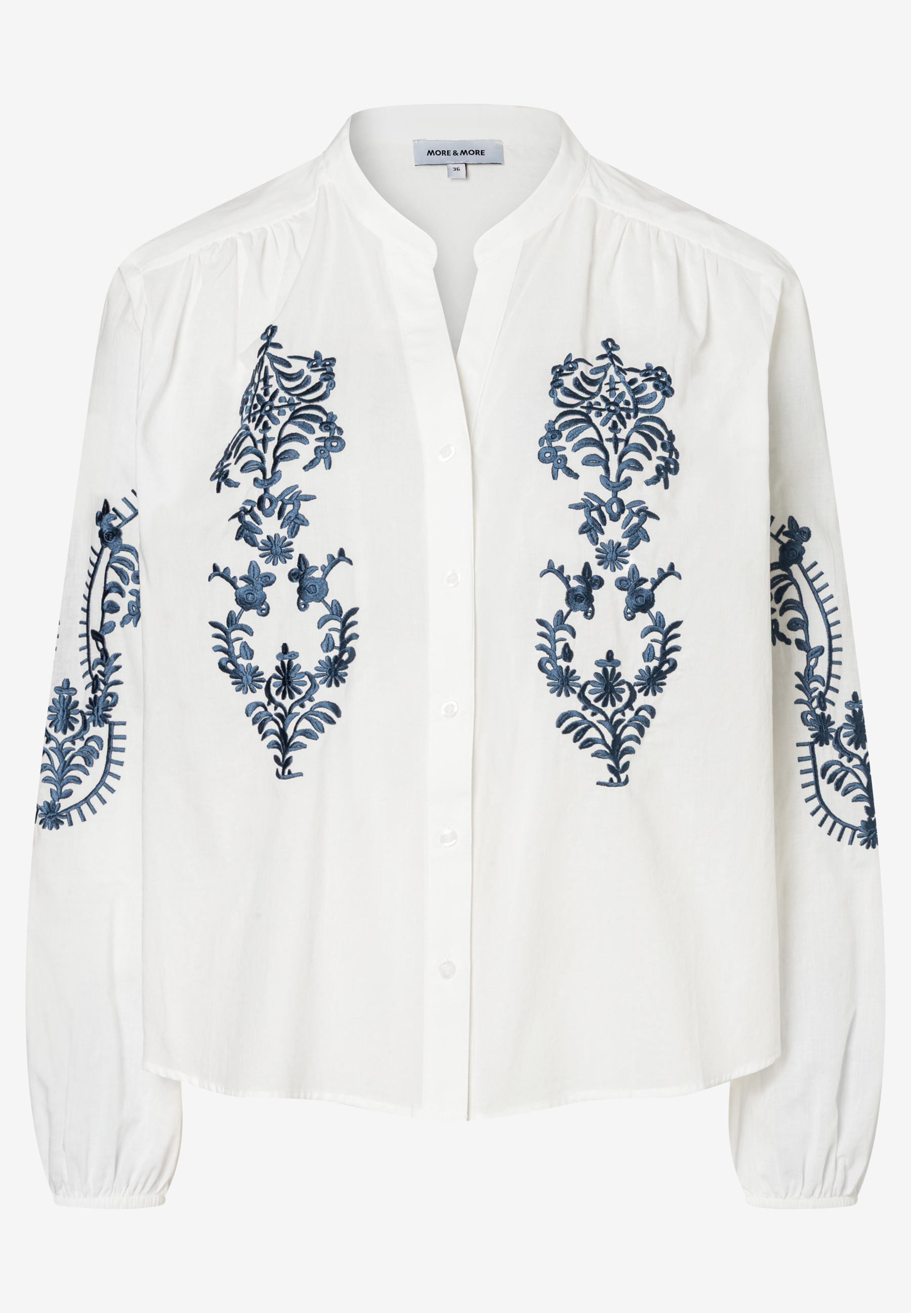 Eine weiße MORE & MORE Bluse mit blauen Blumenstickereien. Eine weiße MORE & MORE Bluse mit blauen Blumenstickereien.