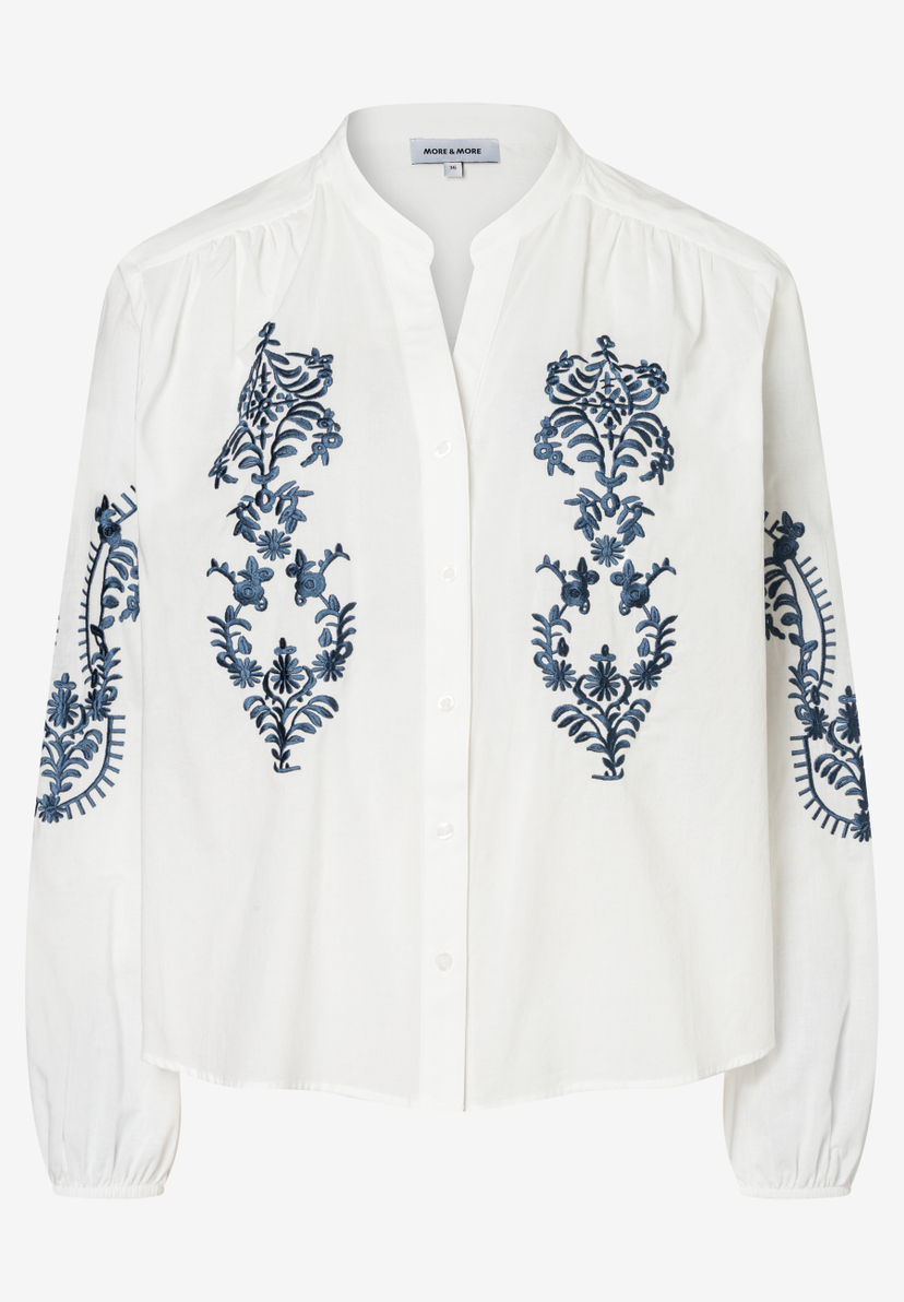 Eine weiße MORE & MORE Bluse mit blauen Blumenstickereien. Eine weiße MORE & MORE Bluse mit blauen Blumenstickereien.