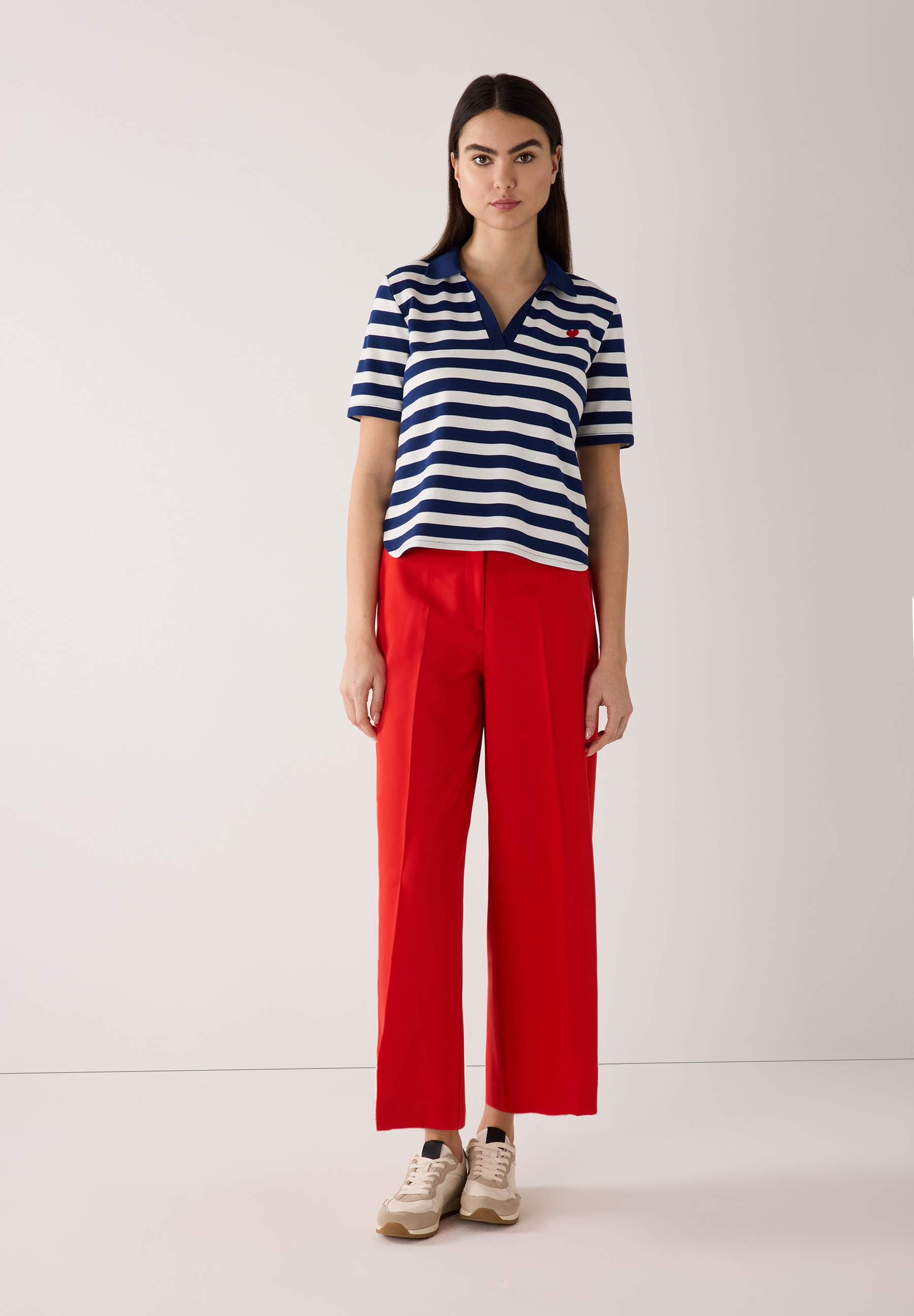 Eine Frau trägt ein gestreiftes MORE & MORE Jersey-Oberteil und eine rote Hose. Eine Frau trägt ein gestreiftes MORE & MORE Jersey-Oberteil und eine rote Hose.