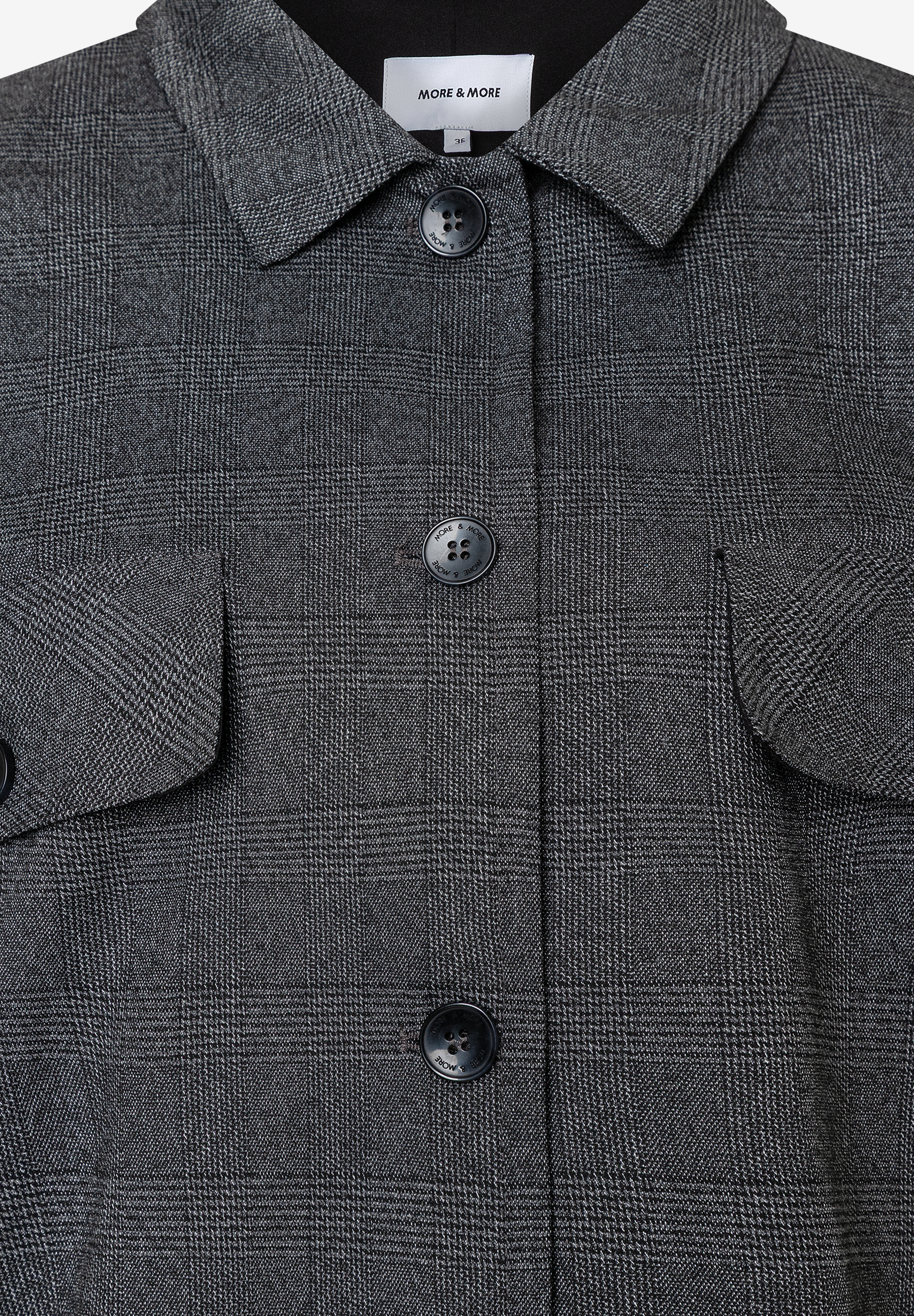 Detailansicht eines karierten MORE & MORE Blazers mit Knöpfen und Webware-Material für angenehmen Tragekomfort. Detailansicht eines karierten MORE & MORE Blazers mit Knöpfen und Webware-Material für angenehmen Tragekomfort.