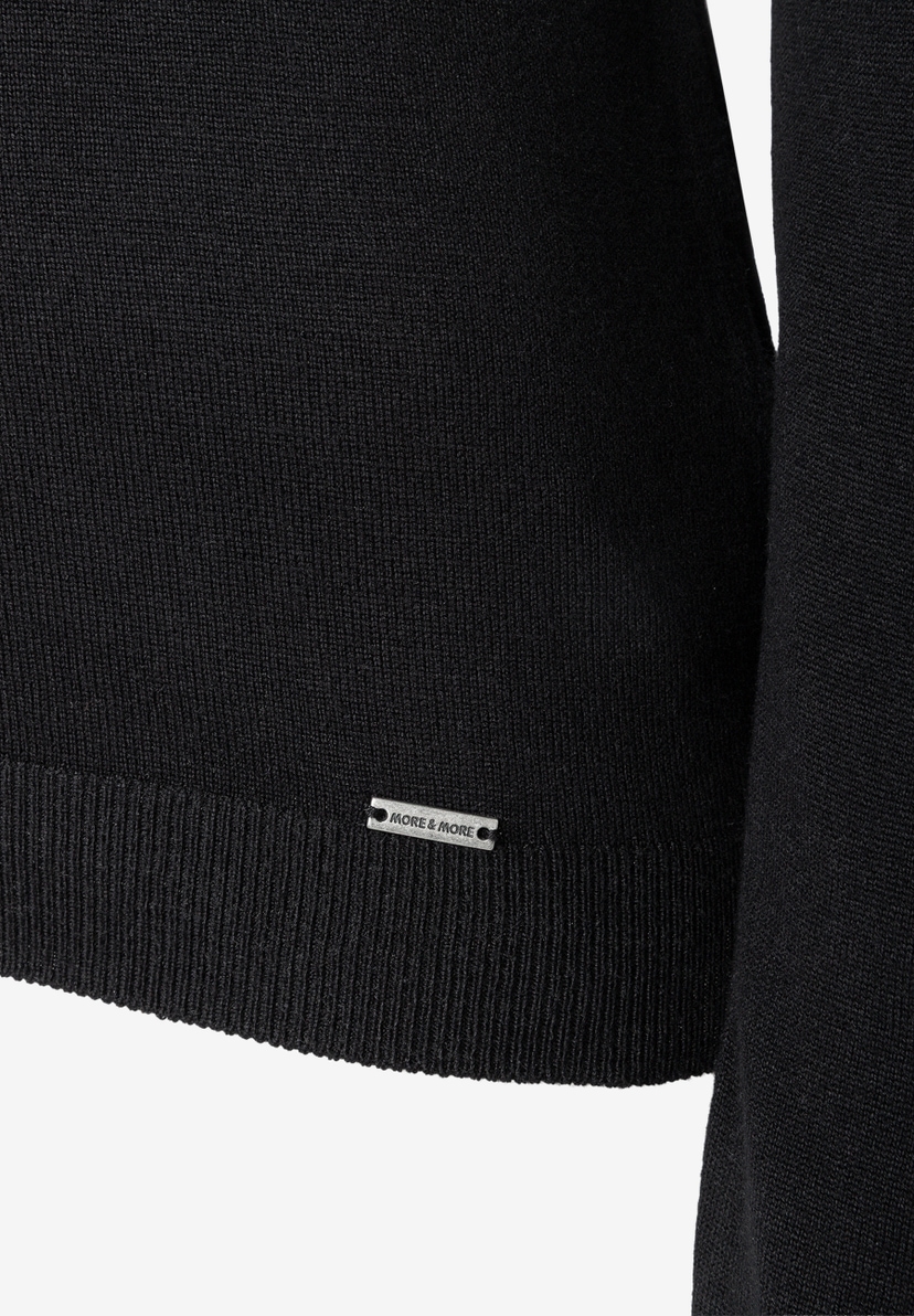 MORE & MORE Feinstrick-Pullover in Schwarz. Nahaufnahme des Saums mit dezentem Markenetikett. MORE & MORE Feinstrick-Pullover in Schwarz. Nahaufnahme des Saums mit dezentem Markenetikett.